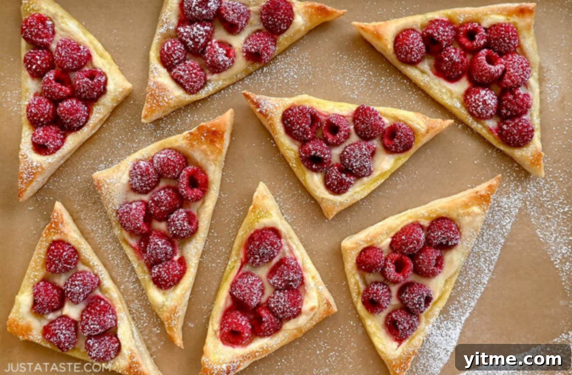 Raspberry Cream Cheese Danish 7 Raspberry cream cheese pastries dusted with confectioners' sugar on brown parchment paper