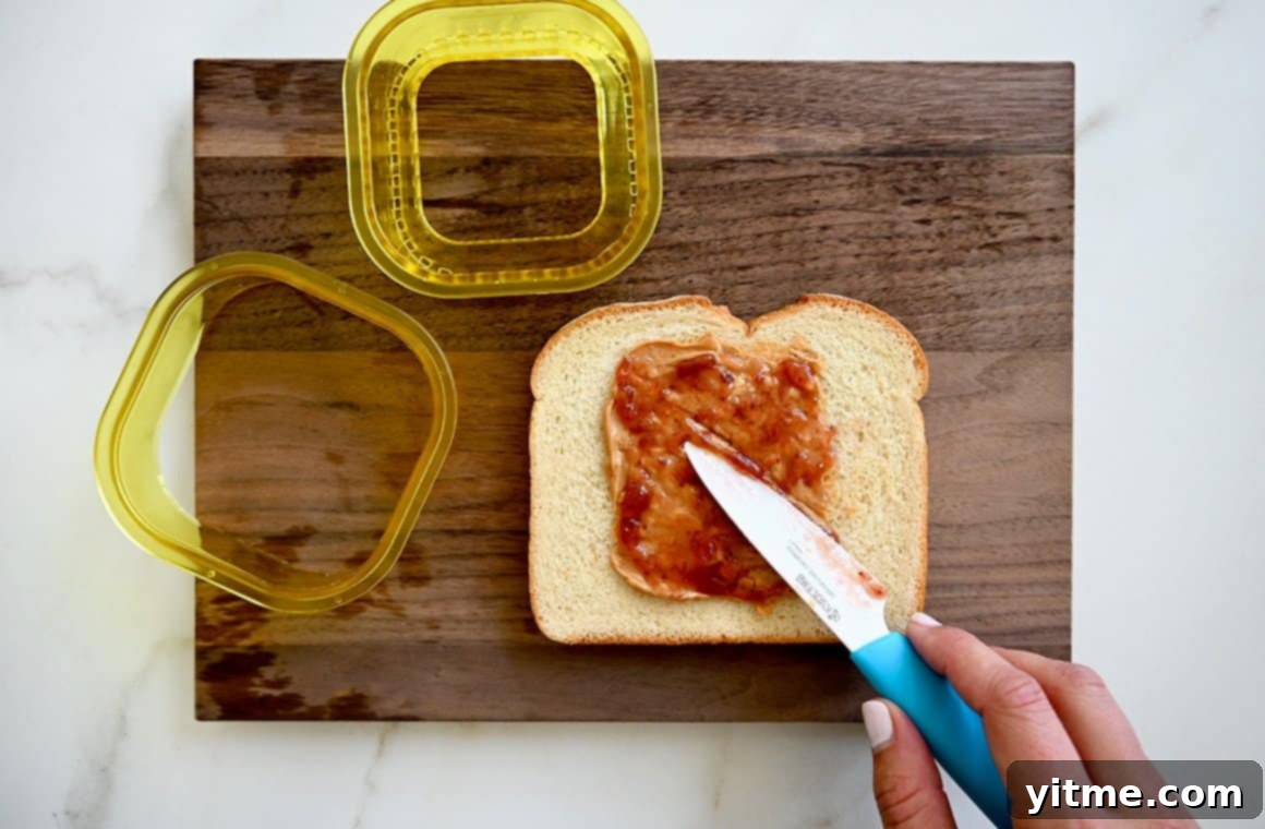Warm and Gooey Air Fried PB&J 3 A wood cutting board with sliced bread and peanut butter and jelly