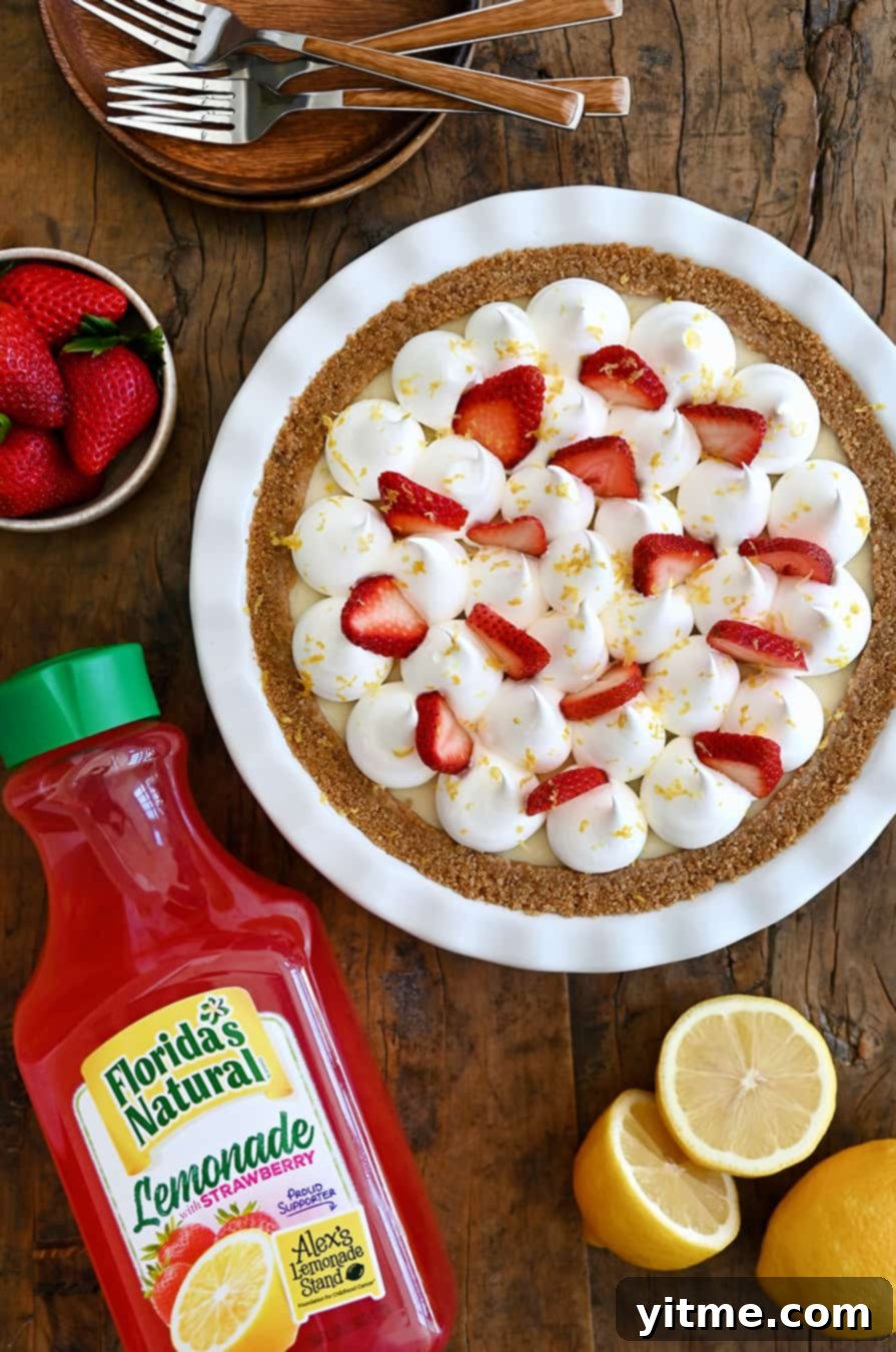 A top down view of a vibrant Strawberry Lemon Icebox Pie with fresh berries and a bottle of strawberry lemonade next to it