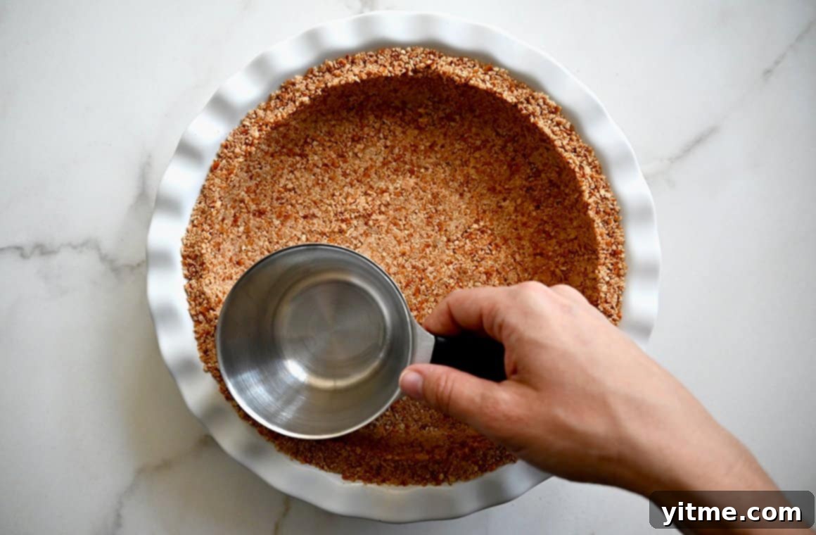 A white ceramic pie plate filled with a golden-brown pretzel crust, ready for the filling
