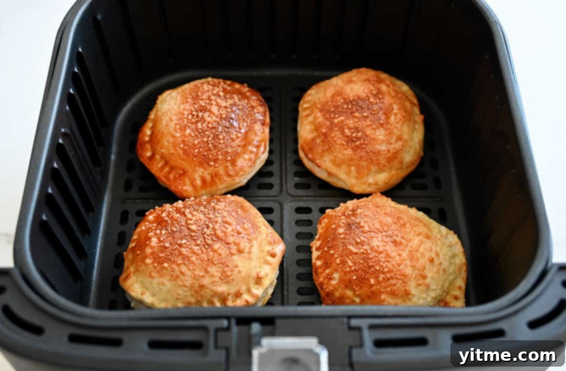 Four golden-brown Air Fryer Pizza Pockets perfectly cooked in an air fryer basket, showcasing their crispy texture.