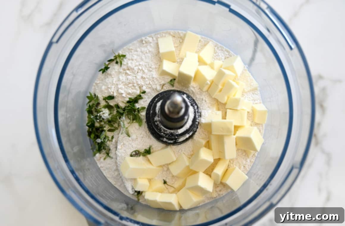 Rustic Blueberry Tart with Honey-Thyme Drizzle 3 Close-up of a food processor bowl containing cubed butter, flour, sugar, and fresh thyme.