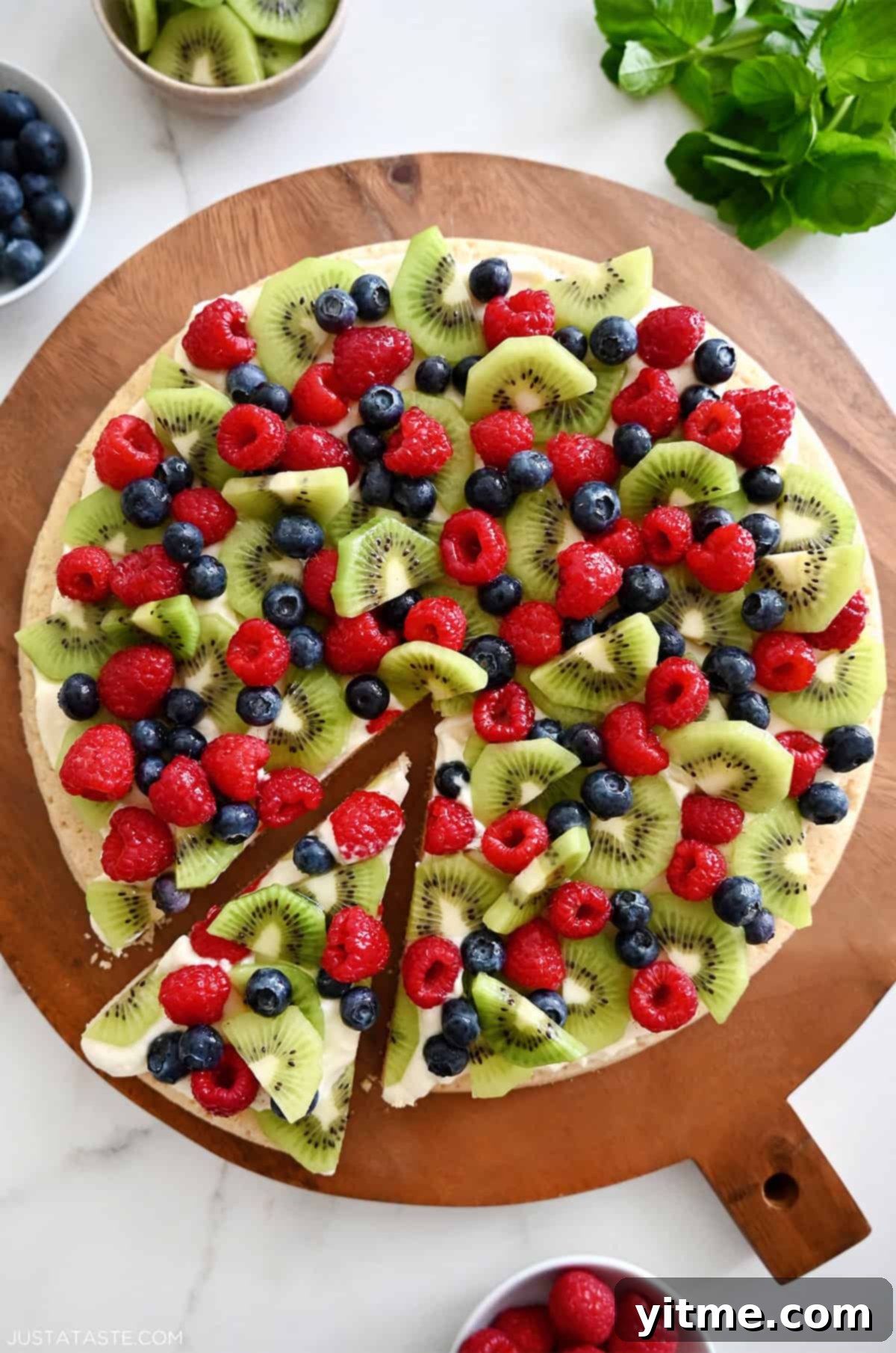 Delicious fruit pizza with sugar cookie crust, cream cheese frosting, and fresh fruit toppings.