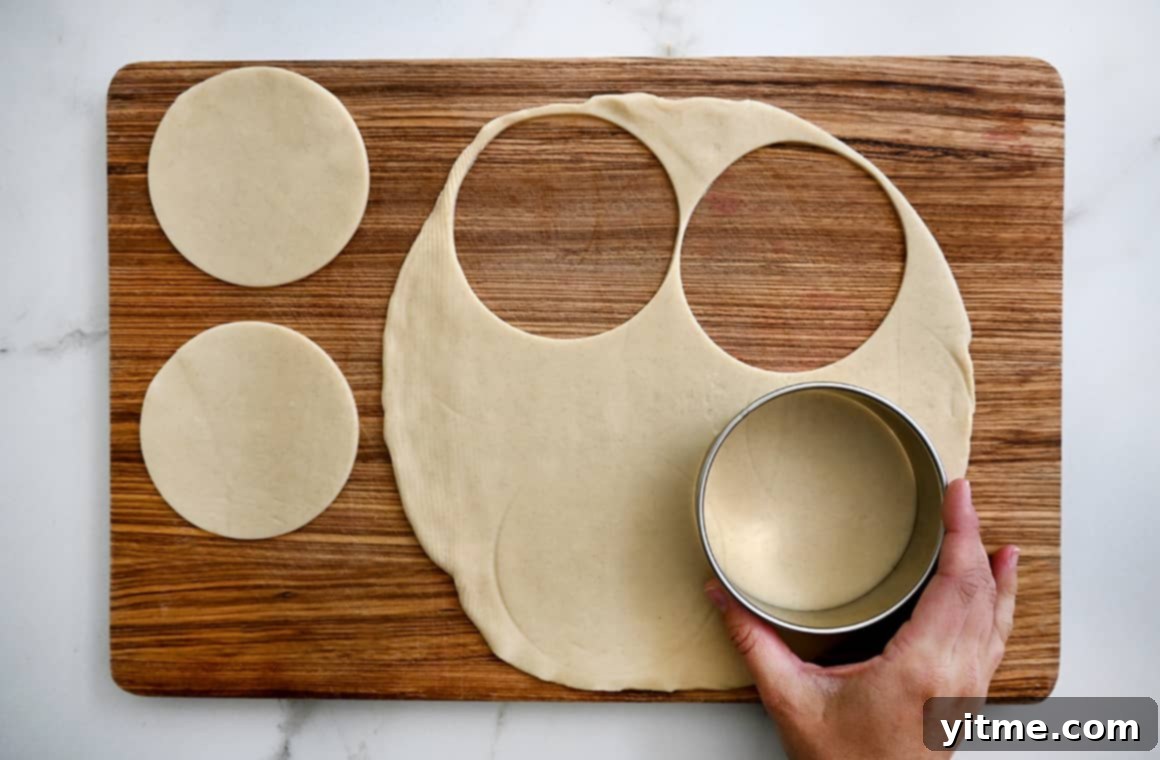 Streusel-Topped Cherry Pie Bites 5 A hand using a round cookie cutter to stamp out perfect dough circles for the mini pie crusts.