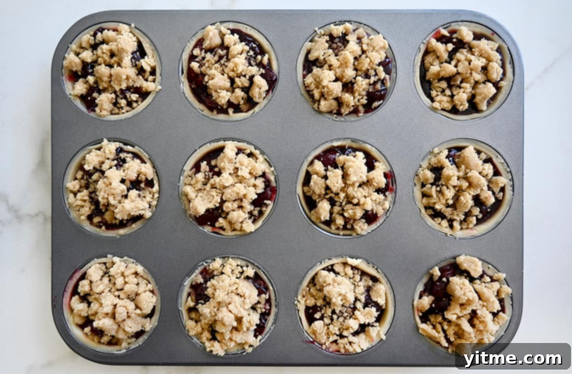 Streusel-Topped Cherry Pie Bites 7 A top-down view of unbaked mini muffin pan pies, filled with cherry mixture and awaiting their streusel topping.