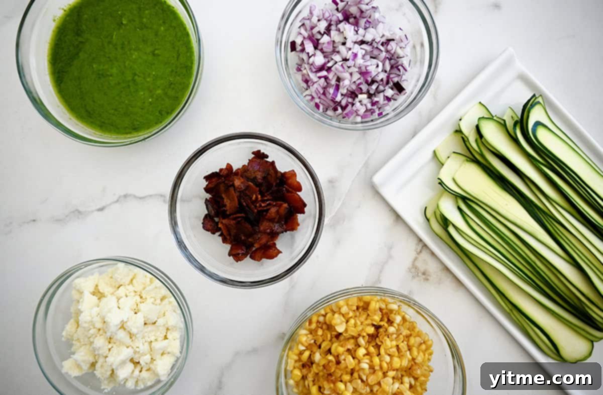 Ingredients for Corn and Zucchini Salad: cotija cheese, corn, bacon, red onion, basil vinaigrette, zucchini ribbons.