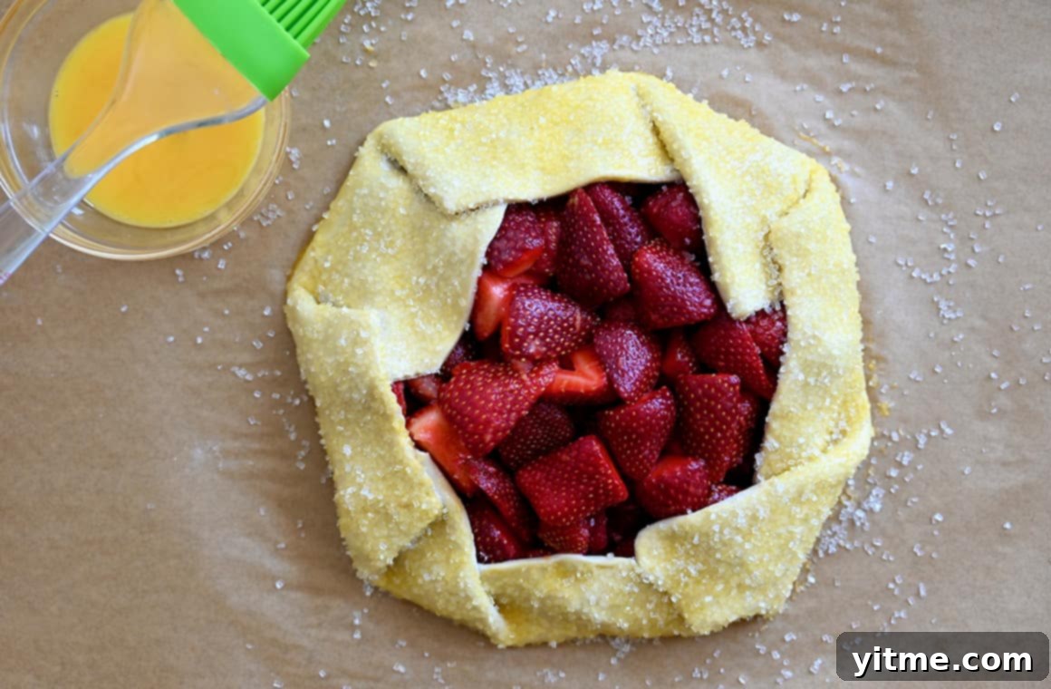 Puff Pastry Galette: A Simple Guide 5 Bowl of egg wash next to an unbaked galette with sanding sugar
