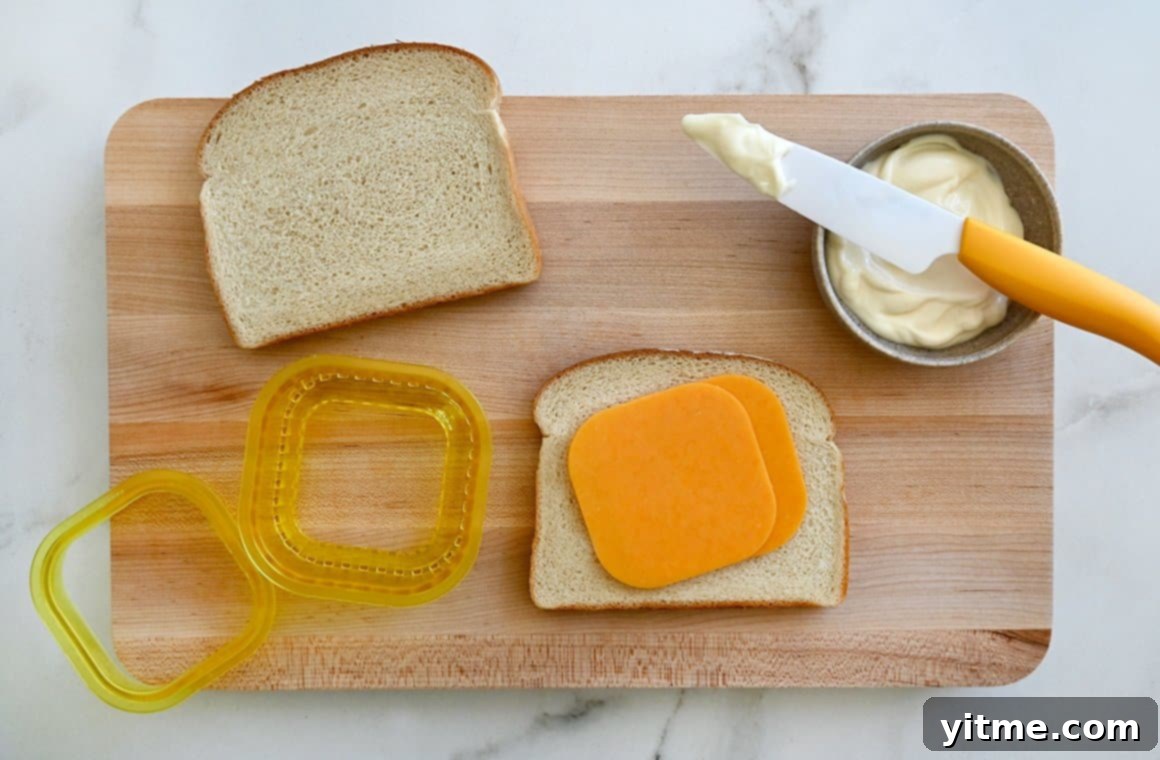 Air Fryer Grilled Cheese Perfection 3 Ingredients for air fryer grilled cheese: bread, cheddar cheese, and mayonnaise on a cutting board.