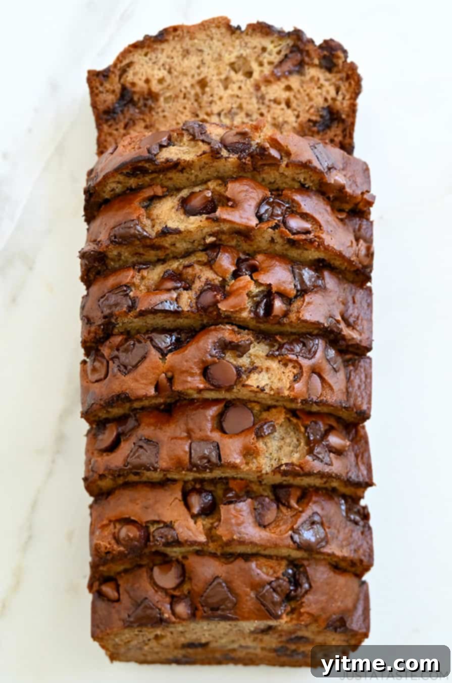 A top-down view of a sliced loaf of Buttermilk Banana Bread studded with chocolate chunks