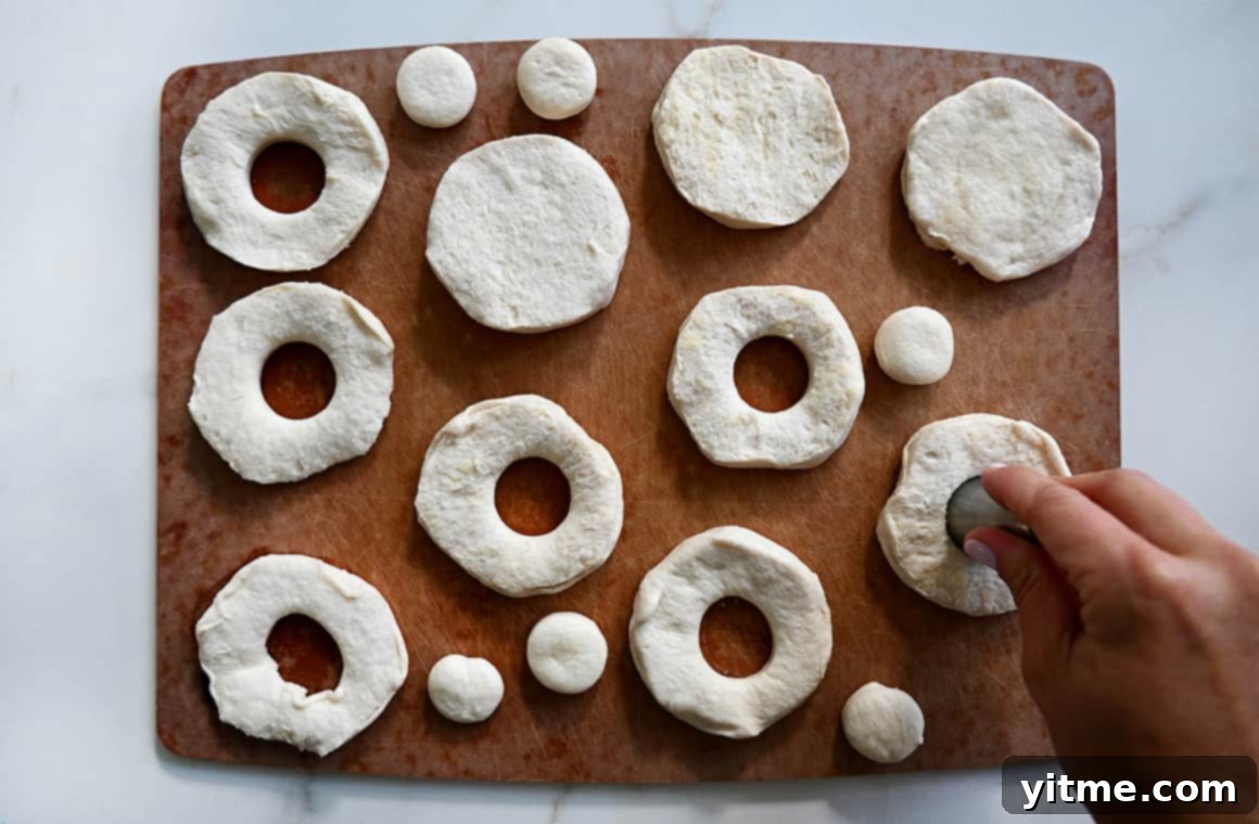 A top-down view of canned refrigerated biscuit dough with cutout centers, showcasing the ease of preparing doughnuts.