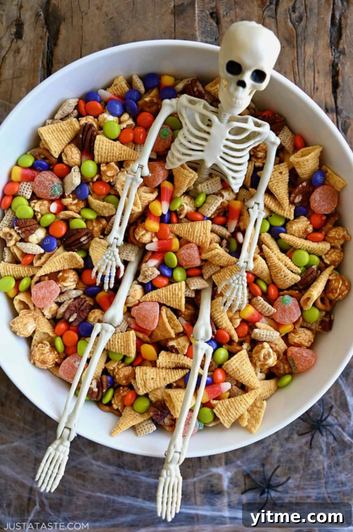 Spooky party mix with a plastic skeleton in a large serving bowl.