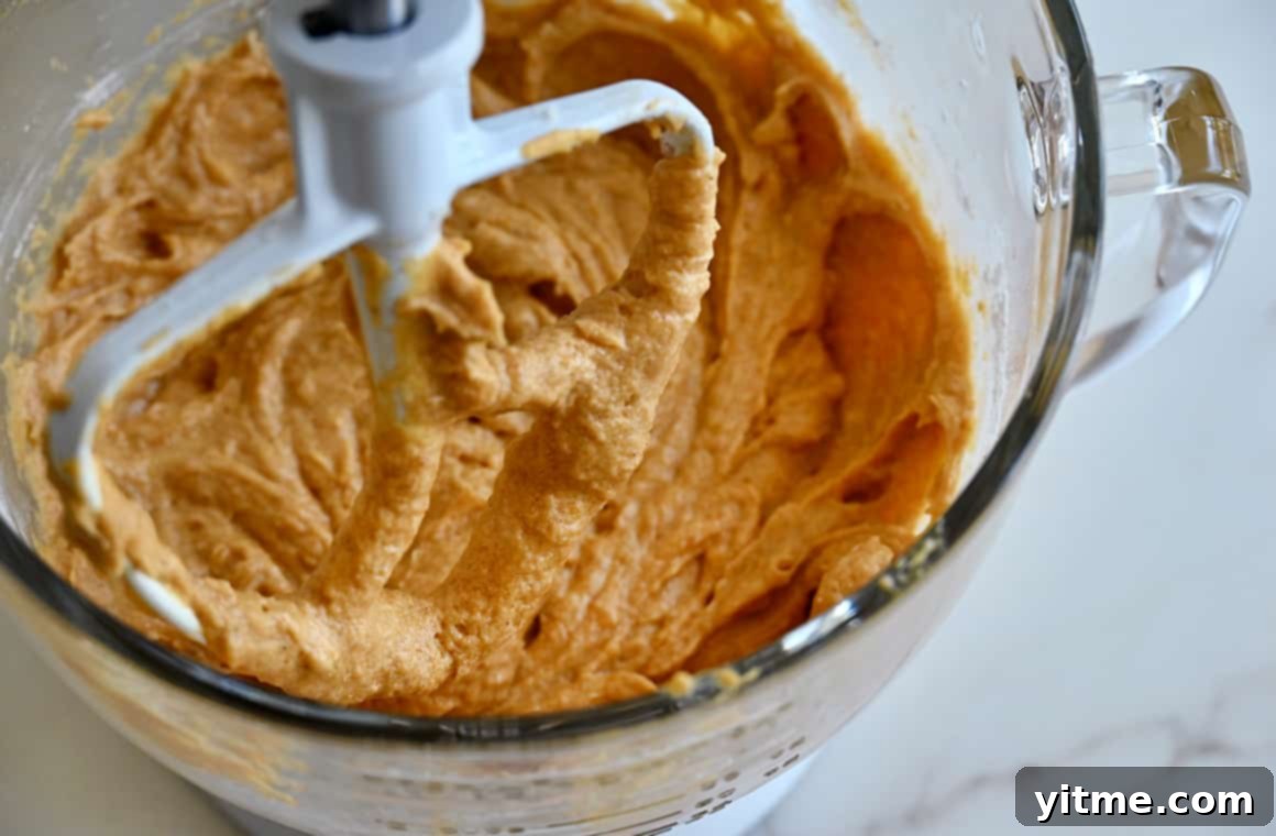 Pumpkin bread batter in a bowl of a stand mixer with the paddle attachment