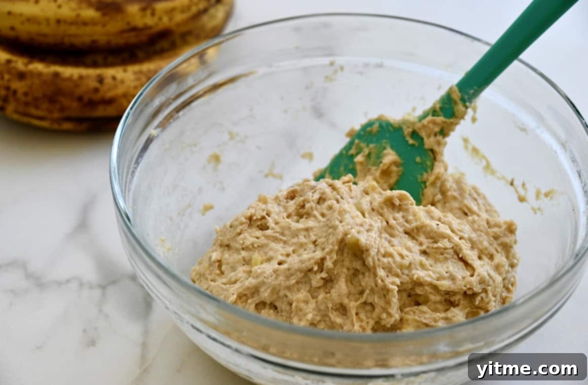 Speedy Banana Fritters 4 Smooth banana fritter batter in a clear bowl with a teal spatula, showcasing its ready-to-fry consistency.
