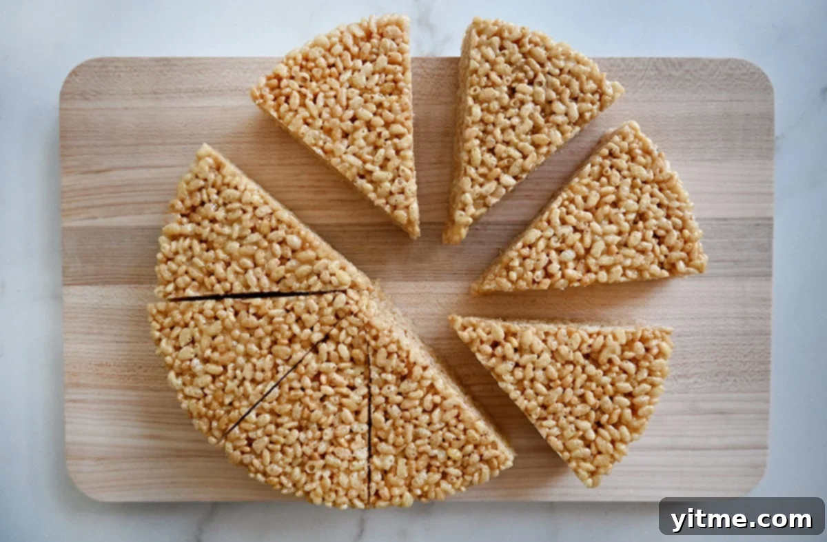 Cooled cereal treats neatly cut into eight triangular wedges on a wooden cutting board.