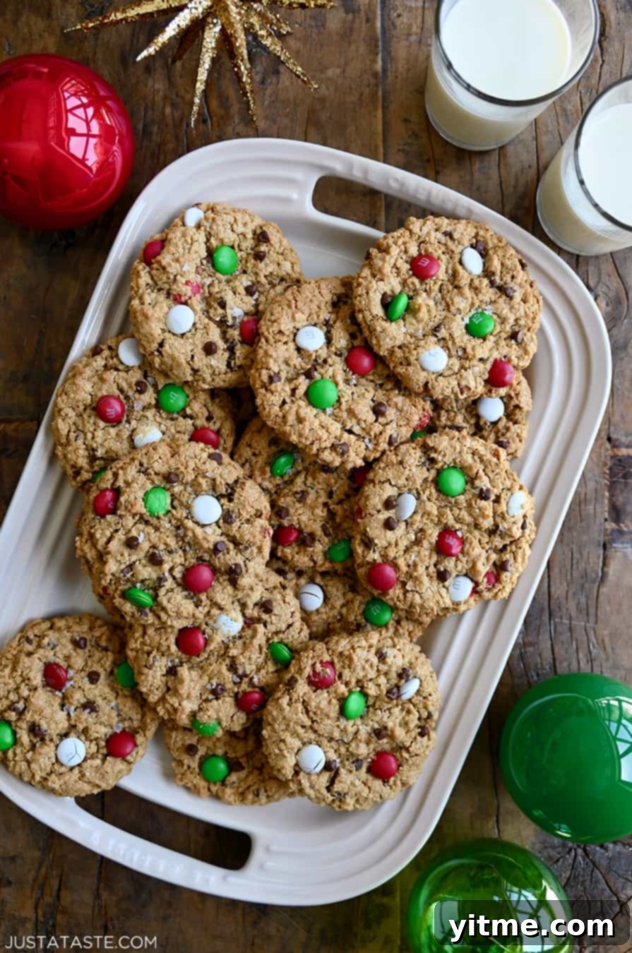 A top-down view of the best Christmas Monster Cookies studded with red, green and white M&Ms on a white serving platter, ready to be enjoyed during the holidays.