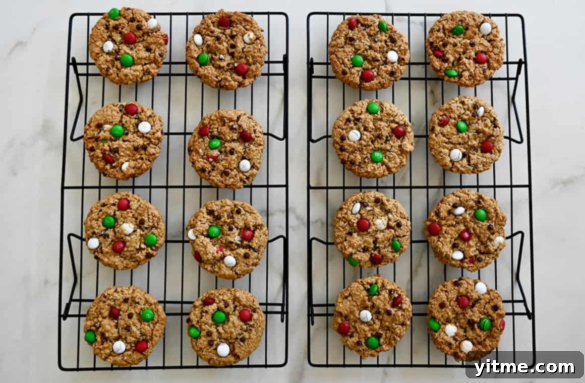 Festive holiday monster cookies cooling on wire racks, showcasing their perfect shape and vibrant M&Ms after baking.