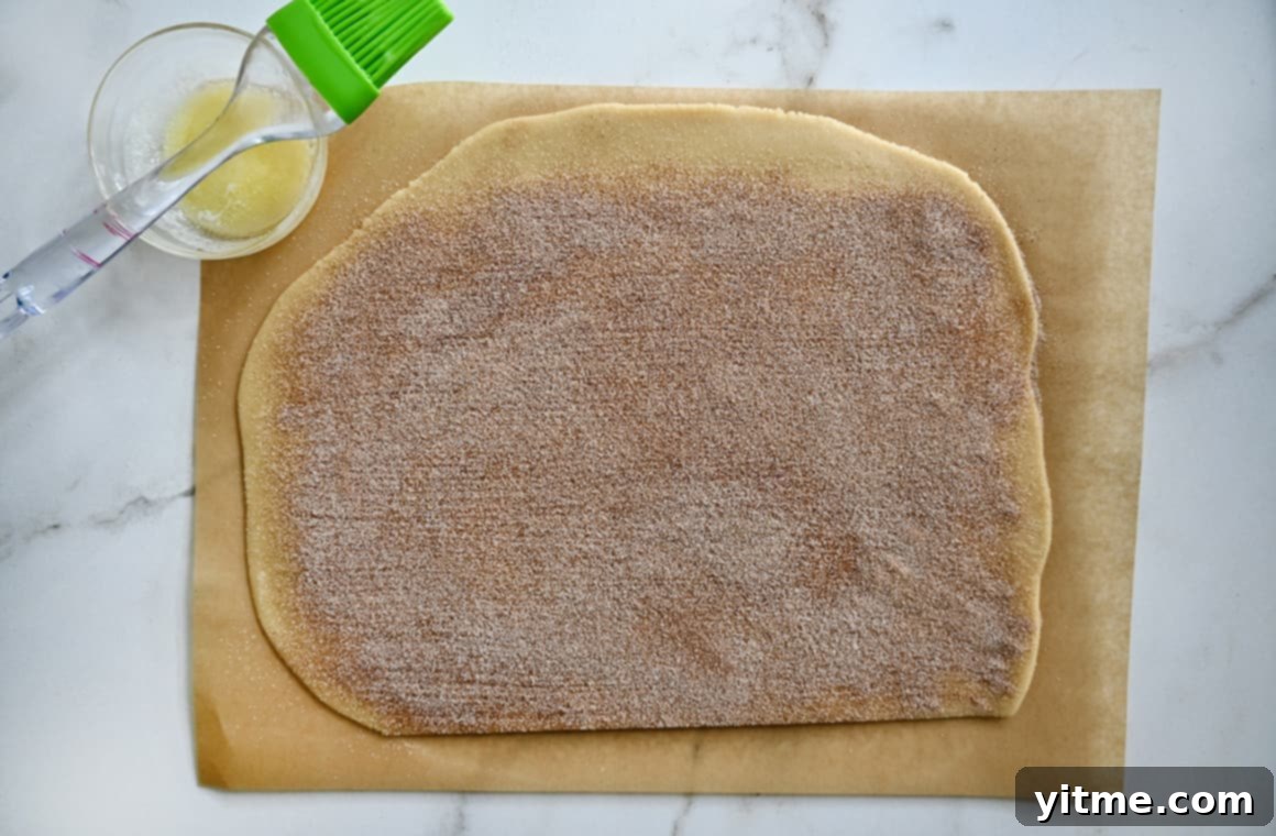 Cinnamon Swirl Cookies 5 Rolled dough on a cutting board next to a bowl of melted butter