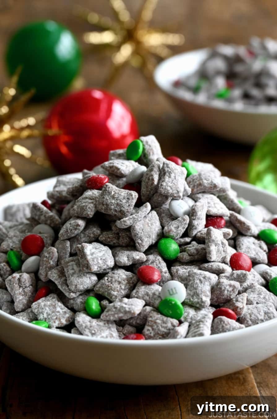 Yuletide Puppy Chow 2 Christmas Puppy Chow with vibrant red, green, and white M&Ms in a white serving bowl, surrounded by festive holiday ornaments.