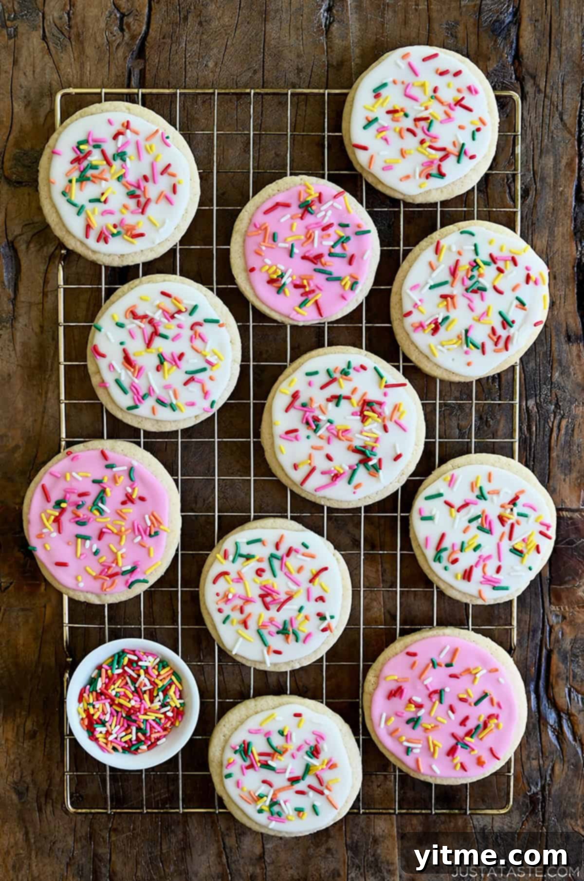 Silky Smooth Sugar Cookie Icing 2 Colorful sugar cookies decorated with homemade 3-ingredient icing and vibrant rainbow sprinkles, cooling on a wire rack.