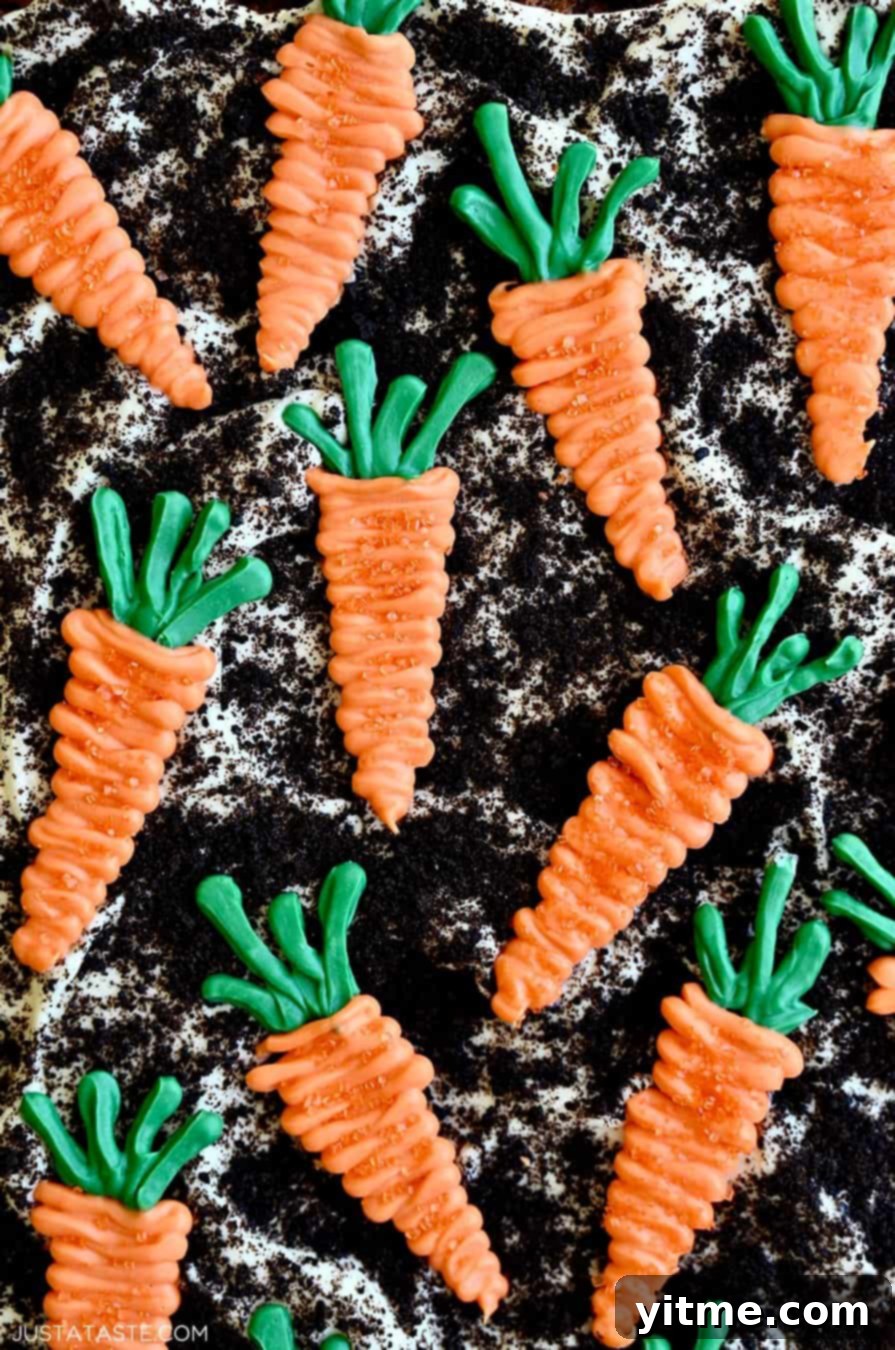 Zesty Carrot Cake Squares with Creamy Frosting 3 Close-up of cream cheese frosting topped with Oreo dirt and candy melt carrots