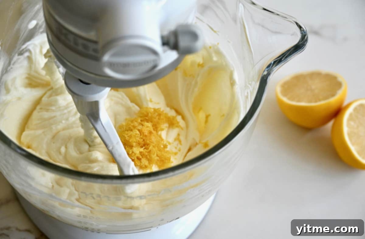 A stand mixer bowl containing batter topped with citrus zest.