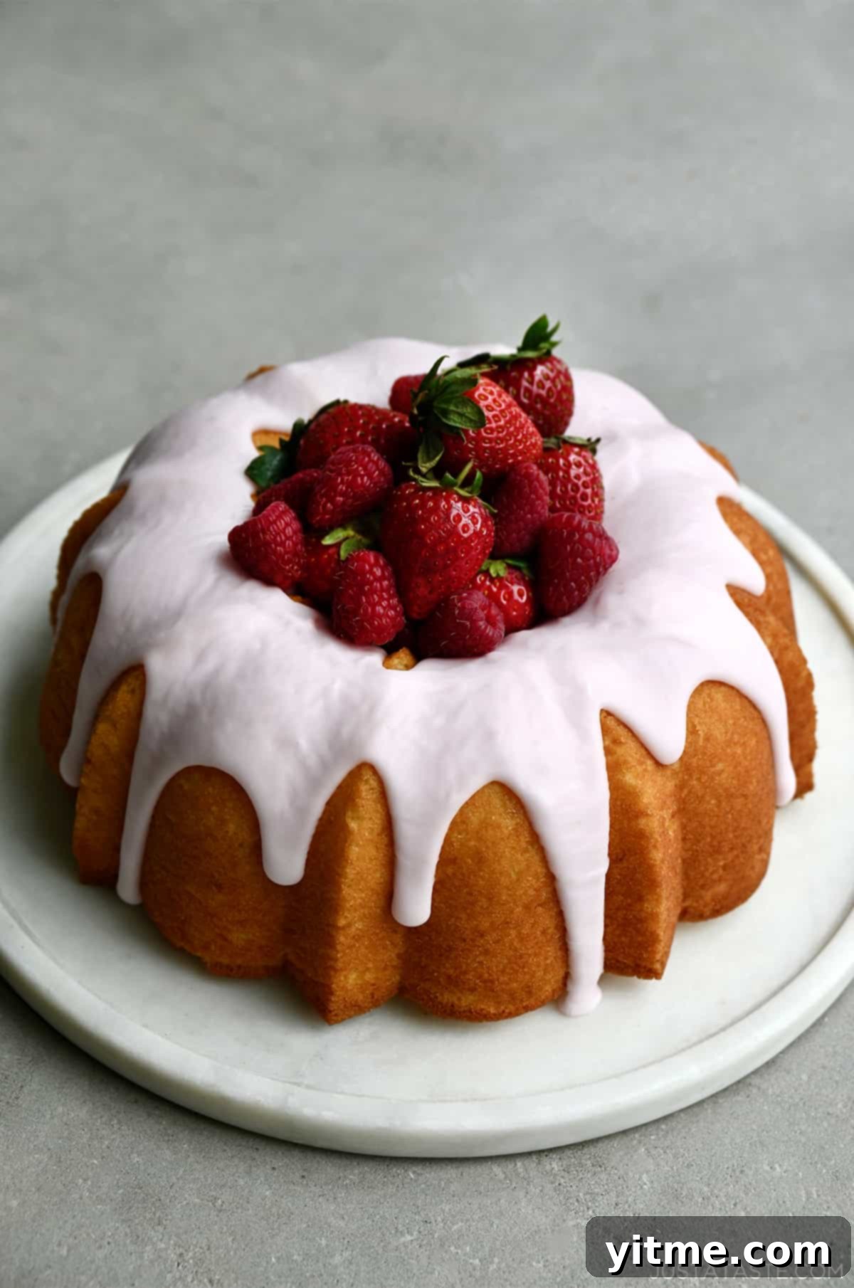 A lemon bundt cake with strawberry glaze and fresh strawberries in the center.