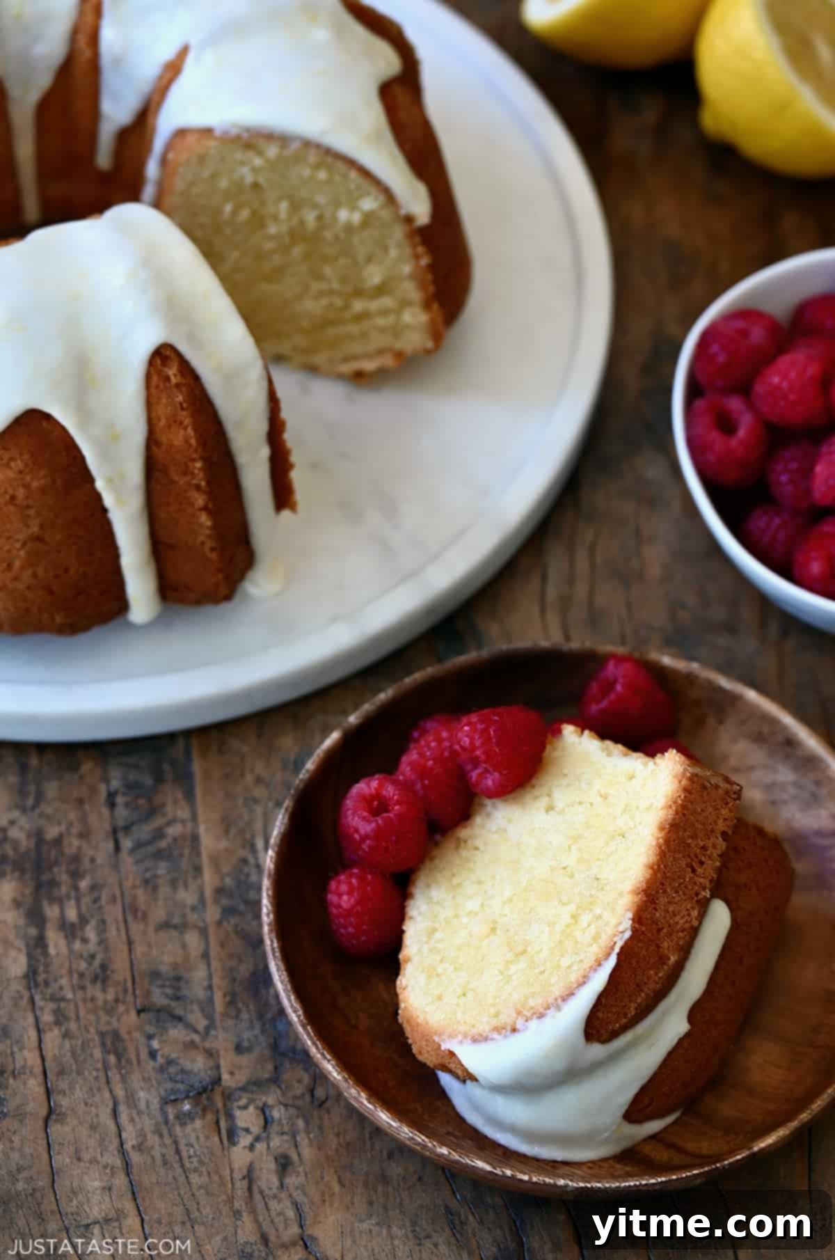 A slice of lemon cream cheese pound cake on a plate with fresh raspberries.