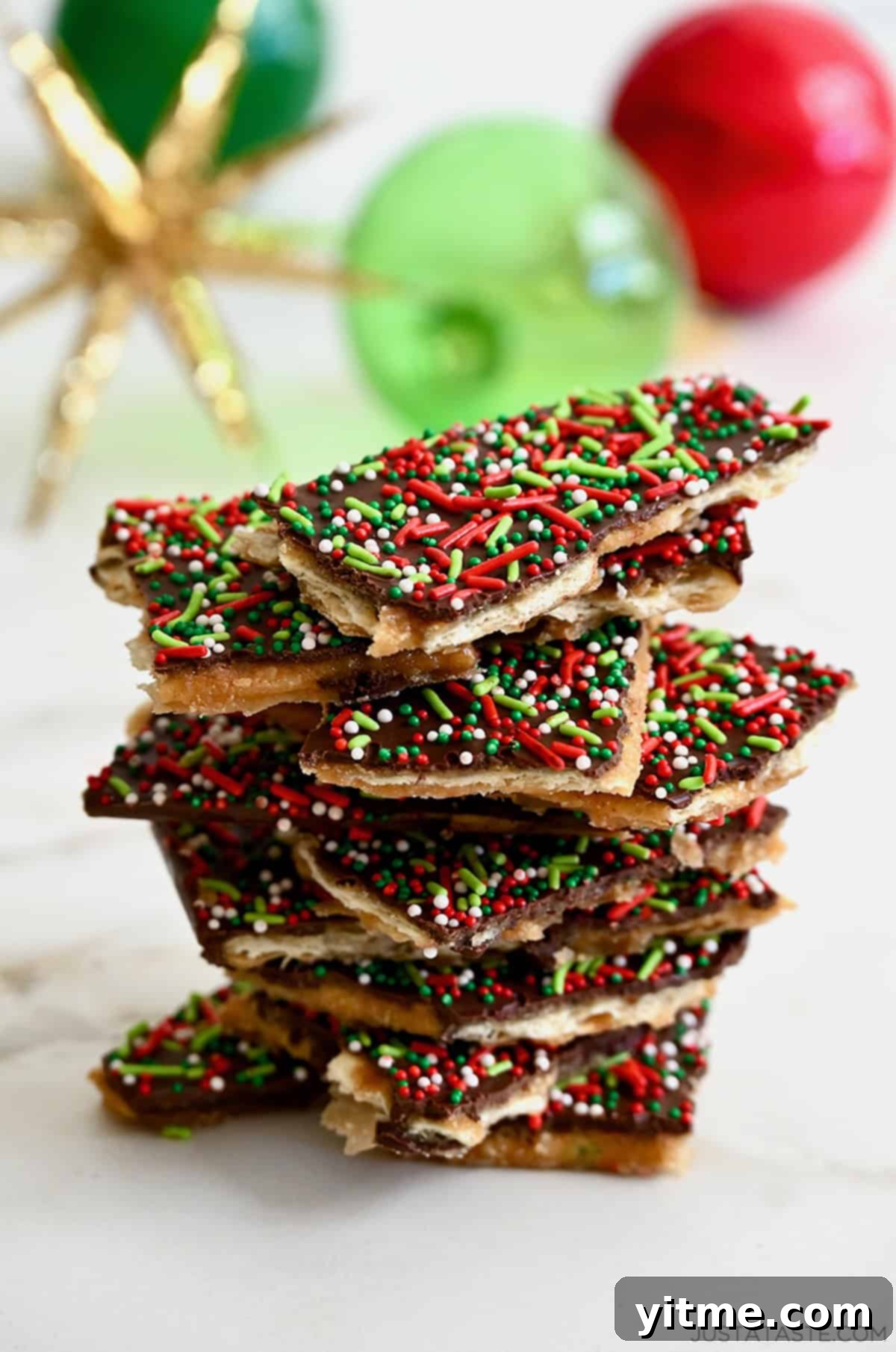 A tall stack of Christmas Crack in front of holiday ornaments