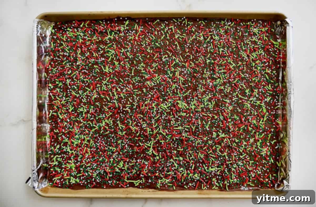 Christmas Crack in a jelly roll pan topped with festive holiday sprinkles