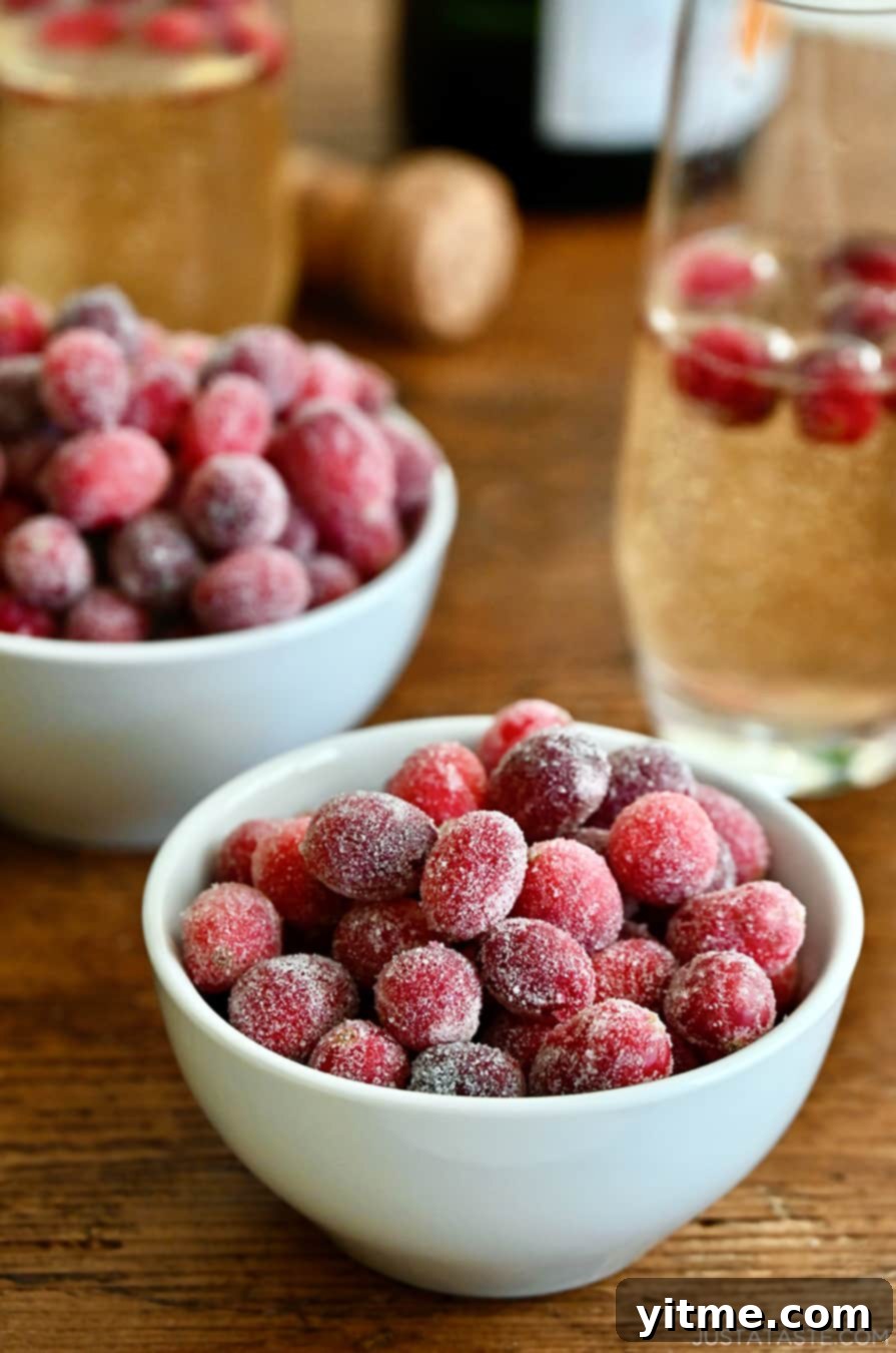 Sugared cranberries in bowls next to a champagne glass with cranberries