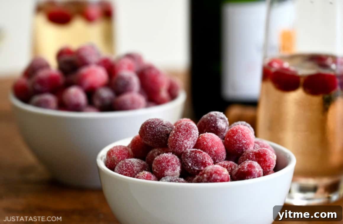 Candied cranberries in a bowl next to sparkling wine
