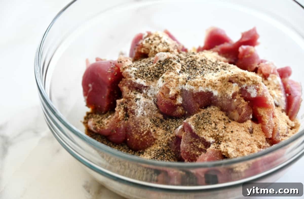Slices of pork tenderloin in a clear bowl topped with a marinade.