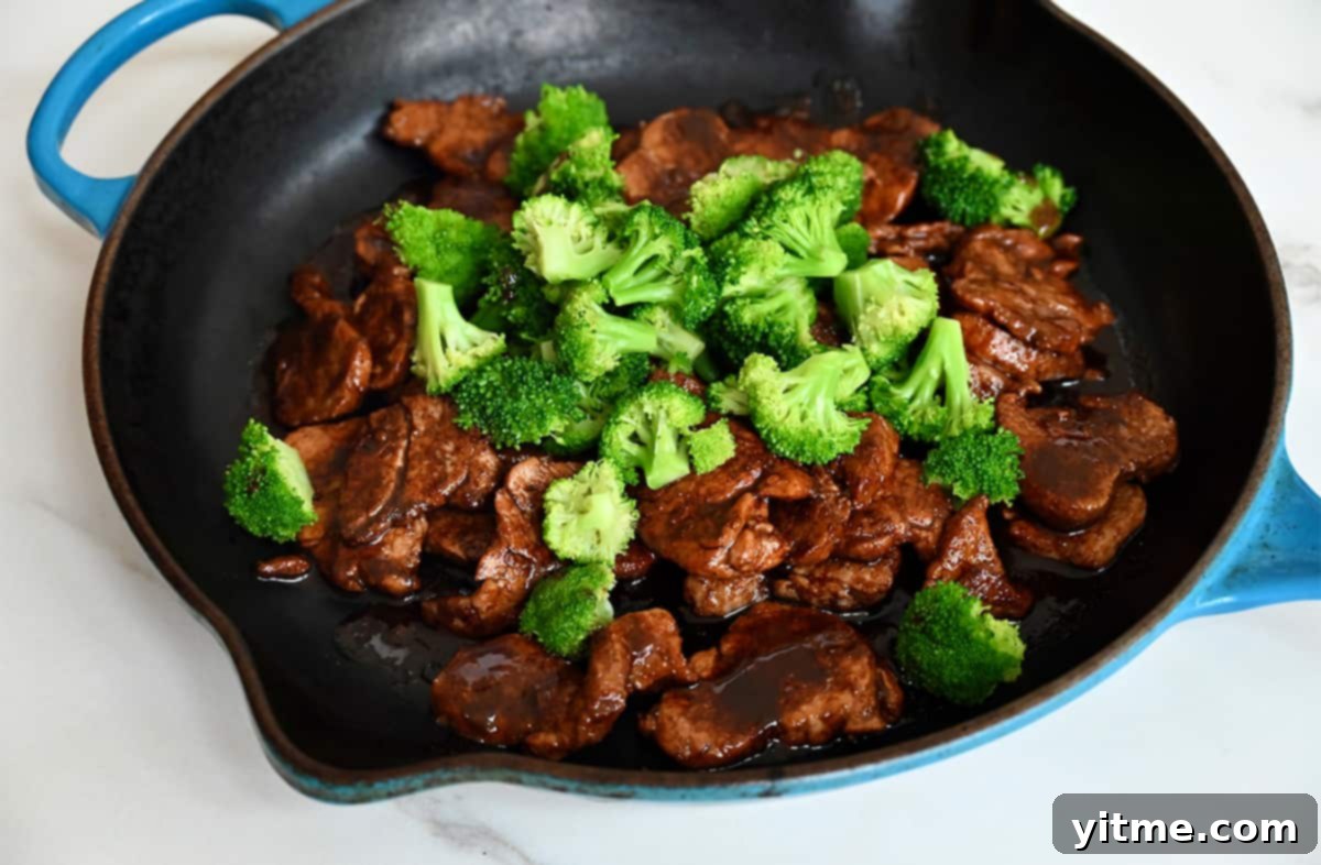 Sautéed pork pieces and vibrant broccoli florets in a large skillet.