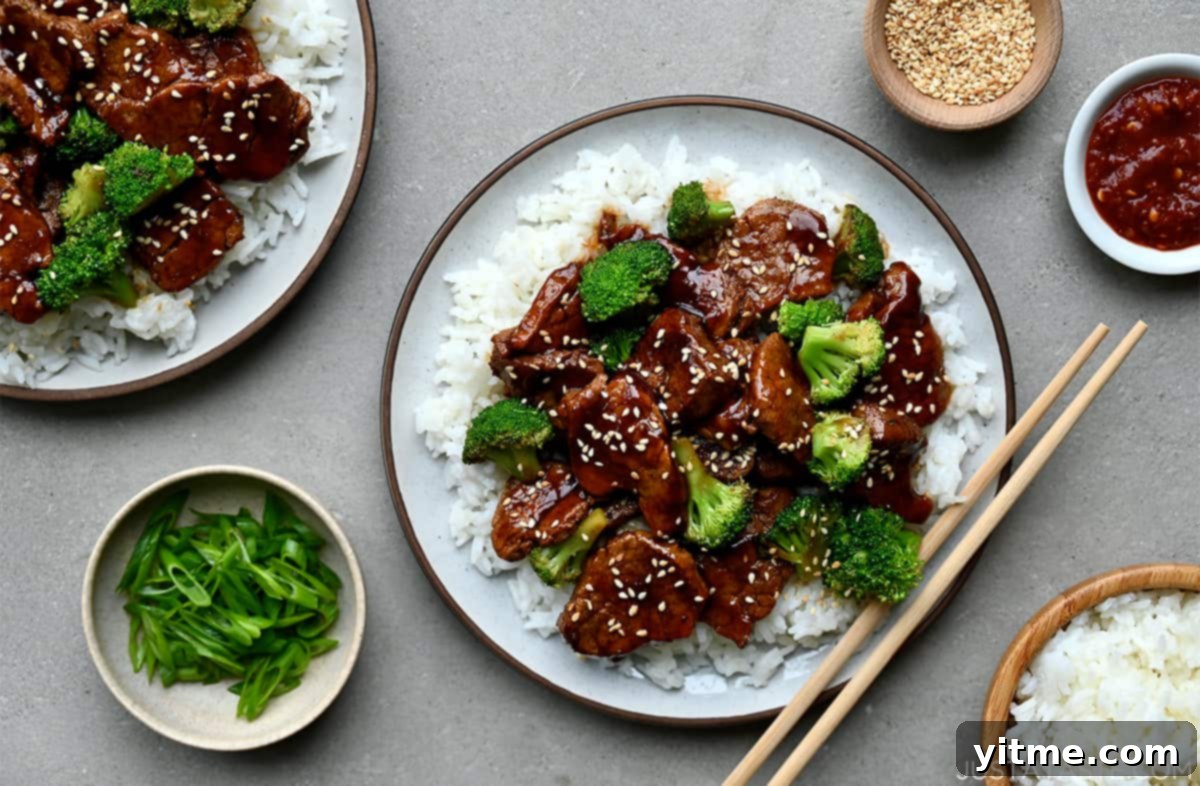 A top-down view of chopsticks resting on a plate containing caramelized pork and broccoli over white rice.
