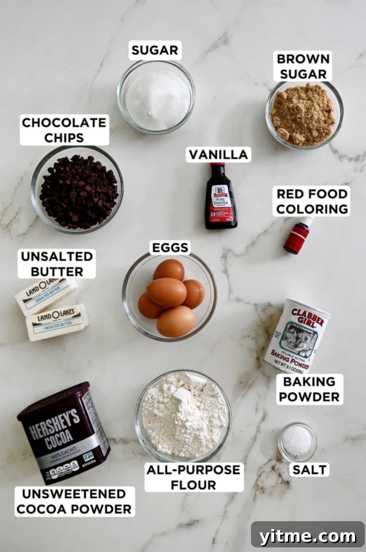 Ruby Velvet Brownie Cookies 3 A top-down view of all the essential ingredients laid out for making red velvet brookies, including softened butter, both white and brown sugars, eggs, all-purpose flour, unsweetened cocoa powder, vibrant red food coloring, and chocolate chips.