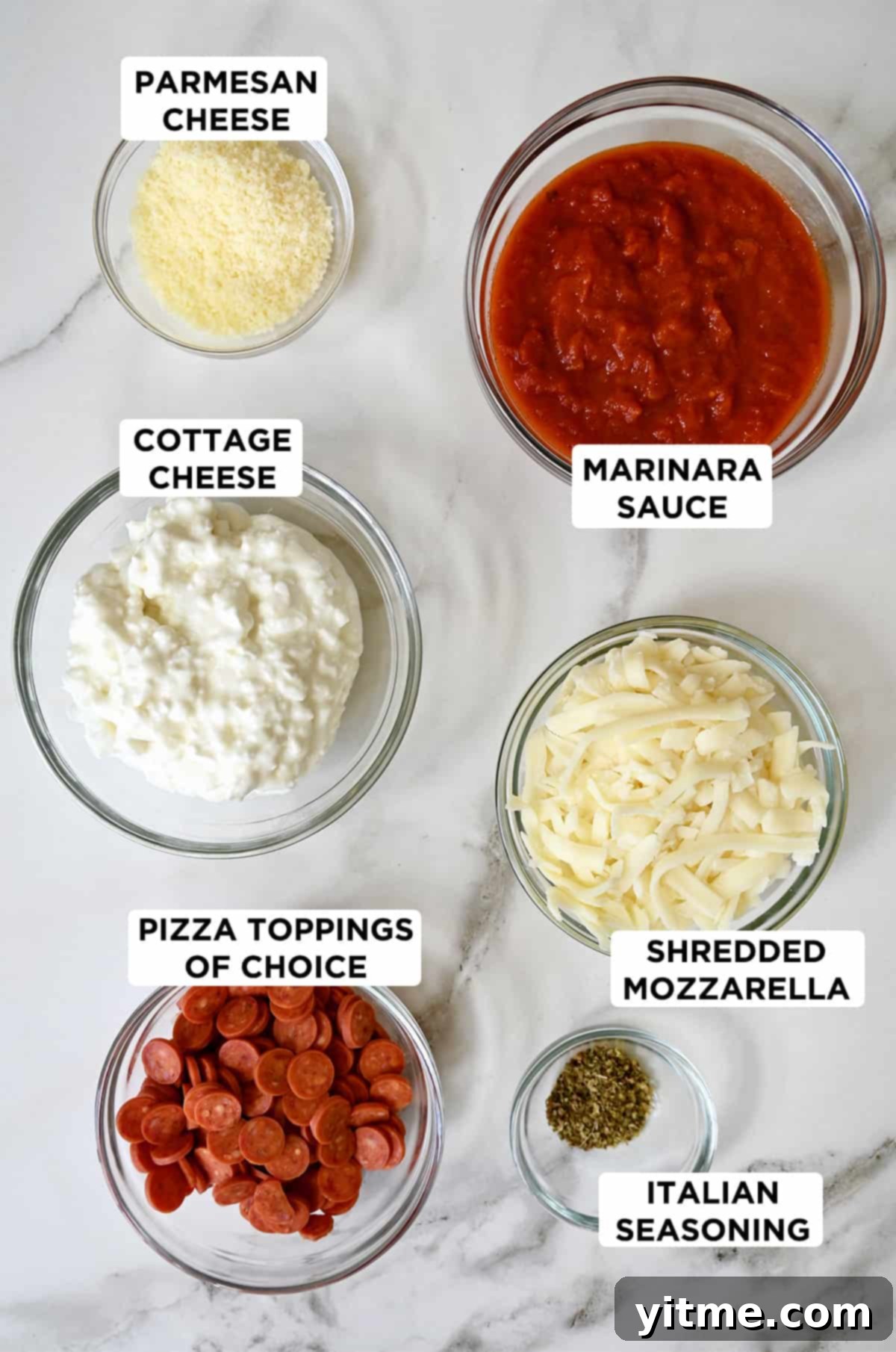 Several clear bowls containing pizza dip ingredients, including cottage cheese, marinara sauce, shredded mozzarella, Italian seasoning, mini pepperoni and grated Parmesan cheese.