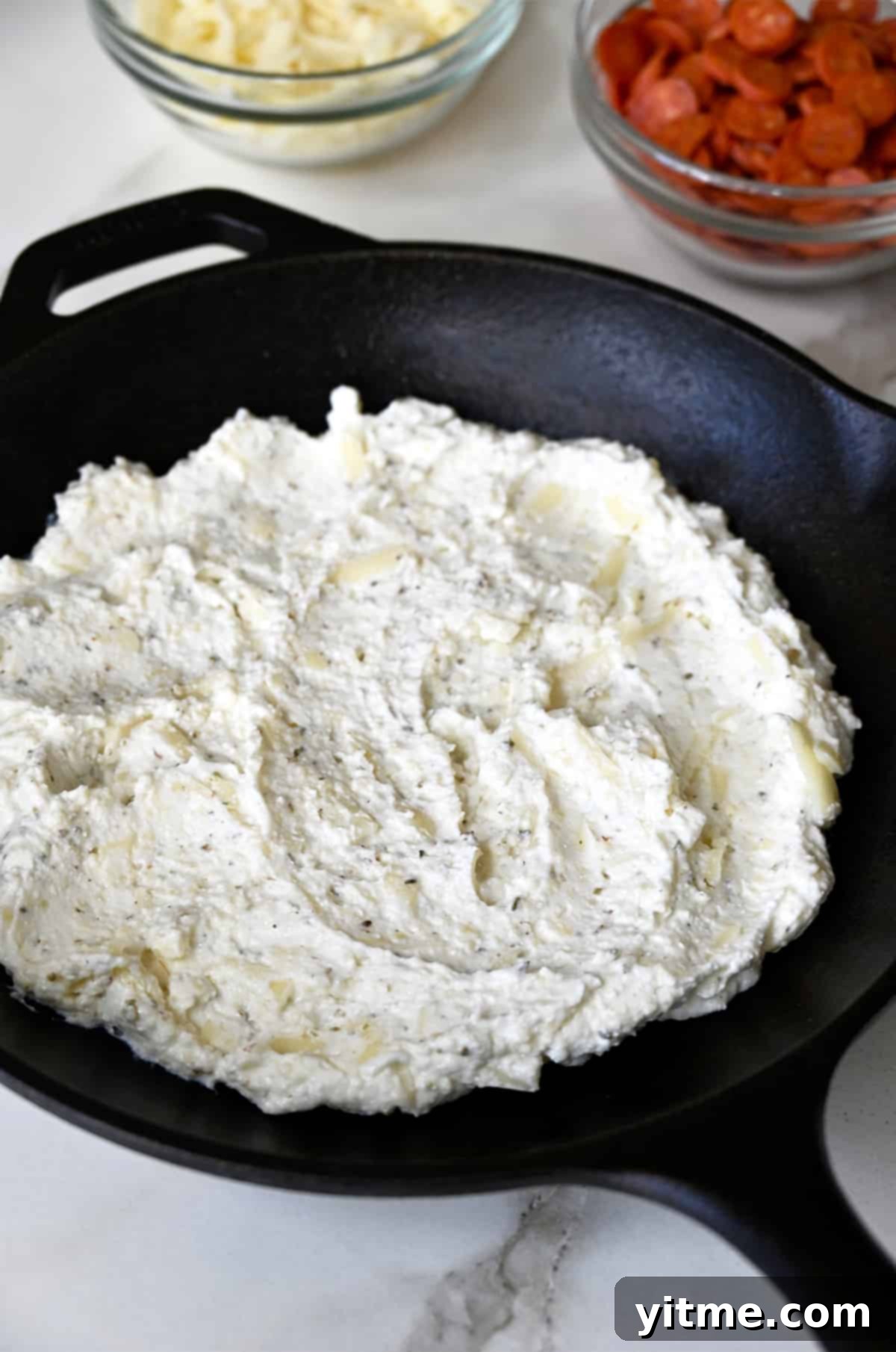 A cheese mixture spread on the bottom of a cast iron skillet.
