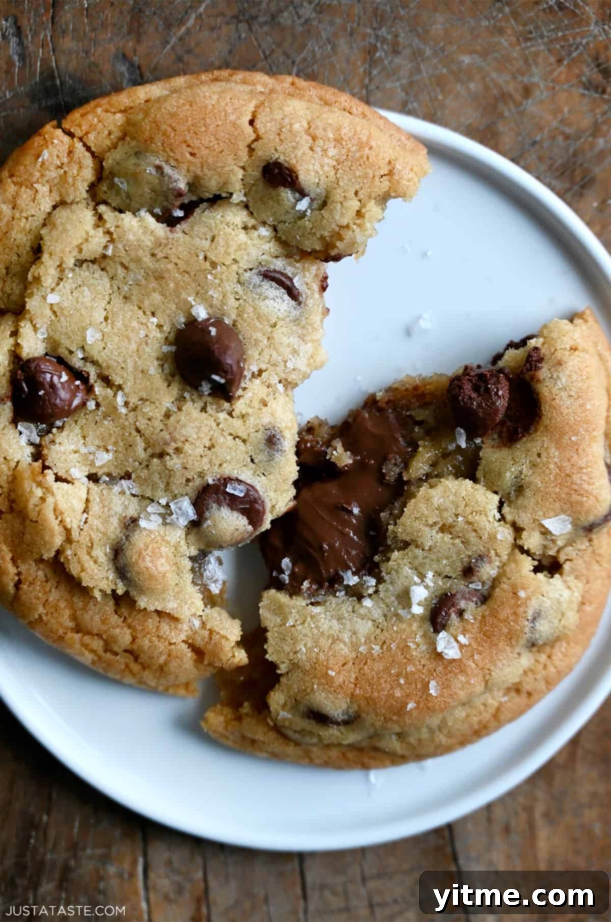A chocolate chip cookie broken in half, revealing a gooey Nutella filling.
