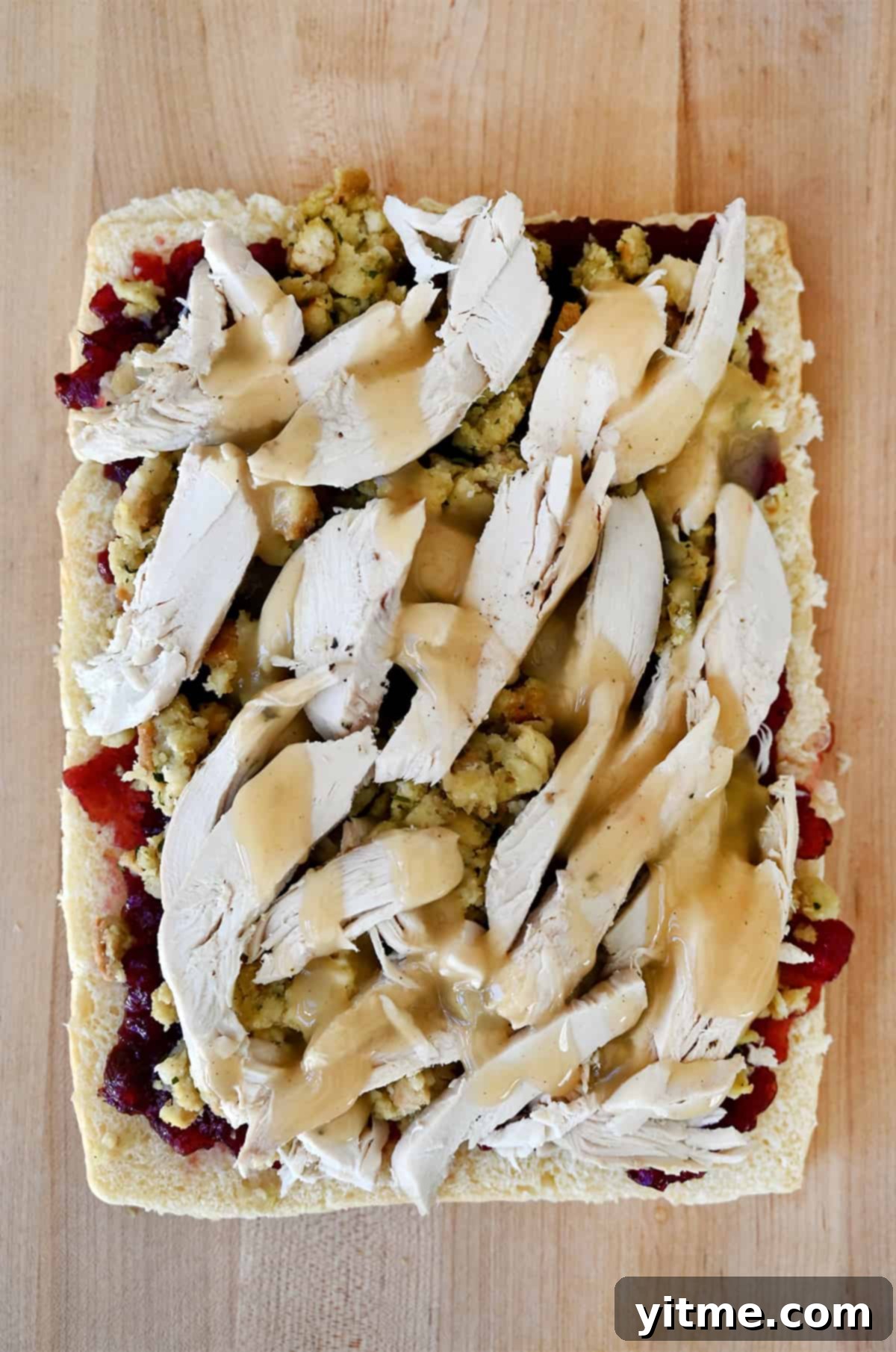 Slider buns topped with cranberry sauce, stuffing, and turkey.