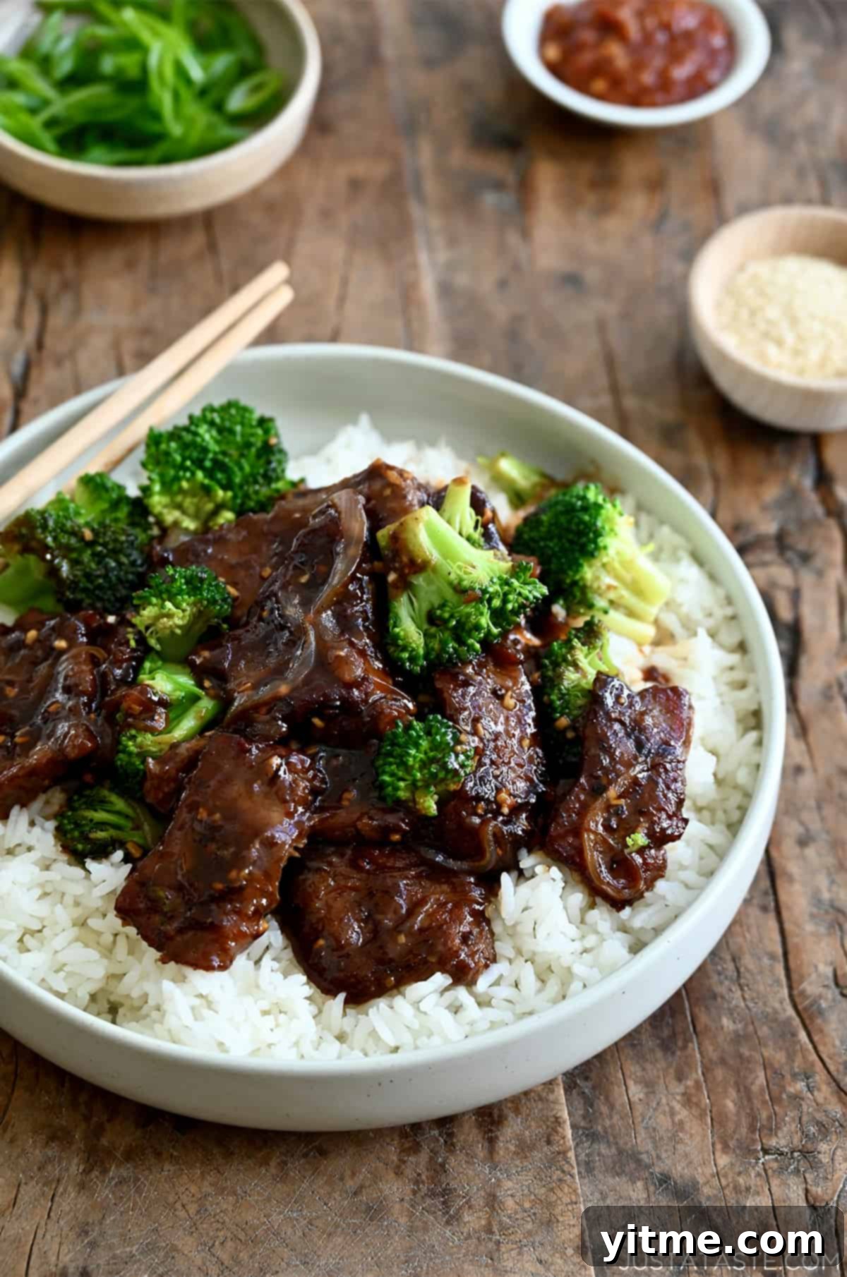 A perfectly plated stir-fried easy beef and broccoli dish served over a bed of fluffy white rice, ready to be enjoyed with chopsticks.