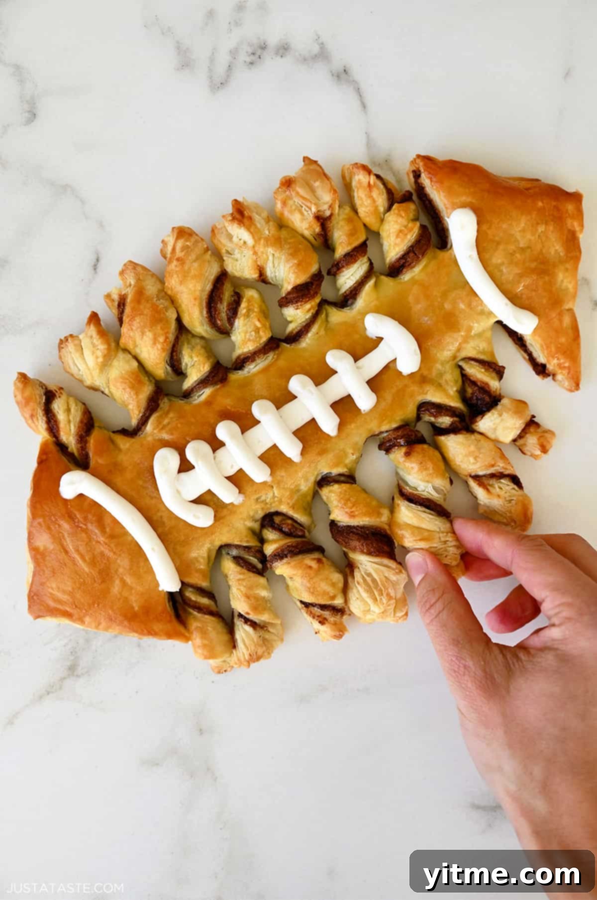 Puff pastry twisted and baked in the shape of a football with vanilla frosting laces, presented beautifully for a game day party.