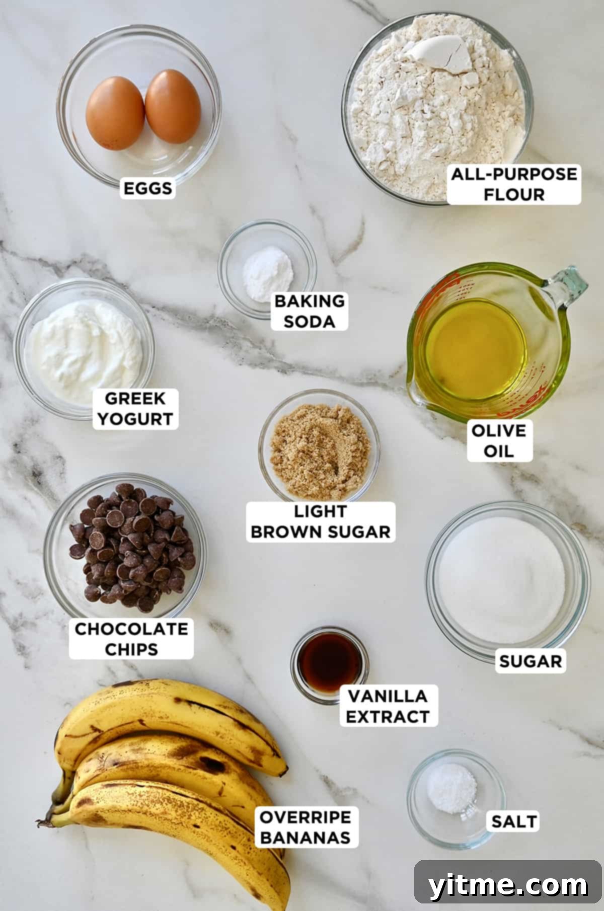 Greek Yogurt Banana Muffins
Deliciously Healthy: Greek Yogurt Banana Muffins 3 Overripe bananas next to bowls containing flour, olive oil, sugar, vanilla extract, salt, chocolate chips, brown sugar, Greek yogurt, baking soda, and eggs.