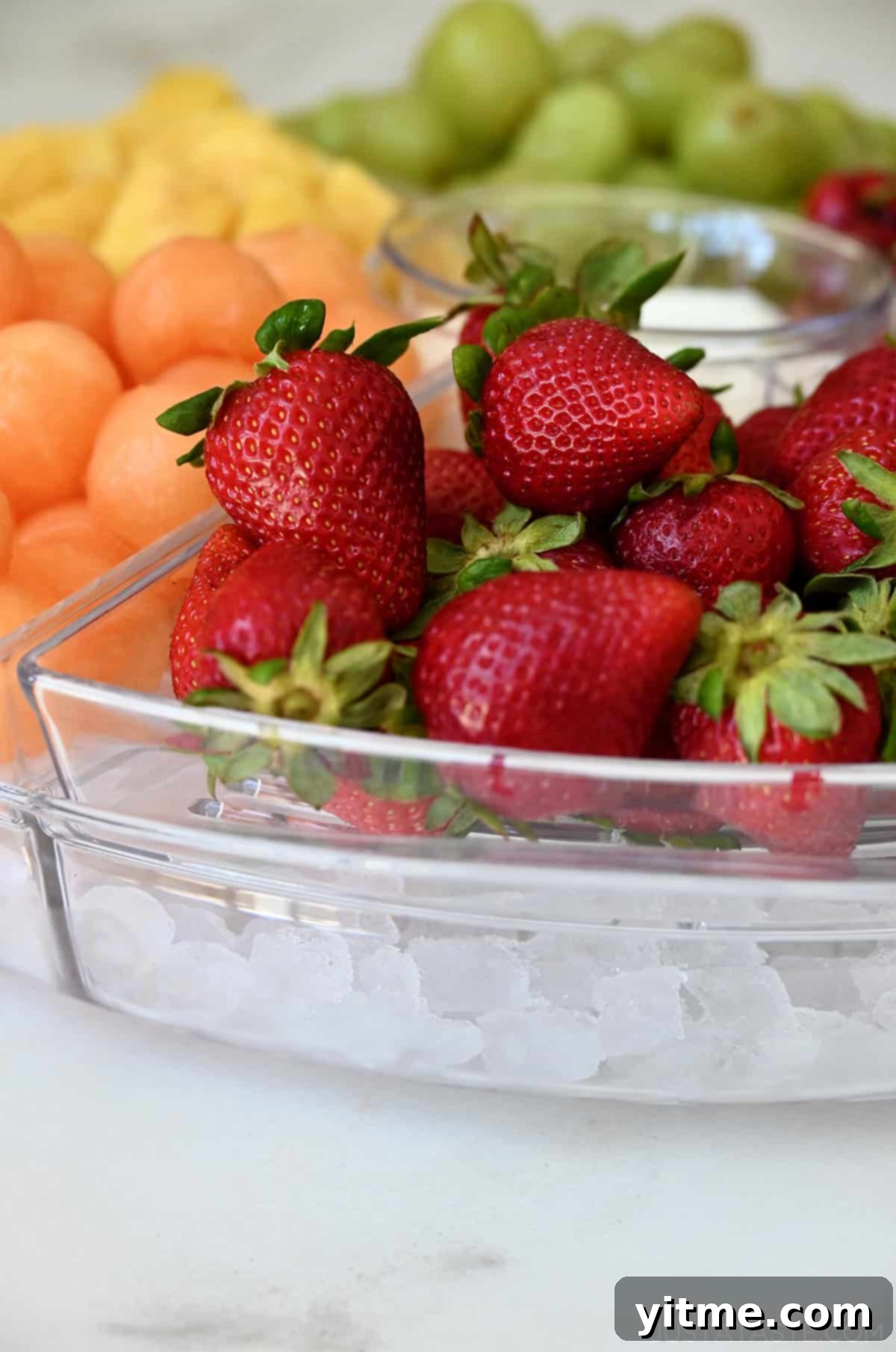 Fresh strawberries in a serving tray over ice.