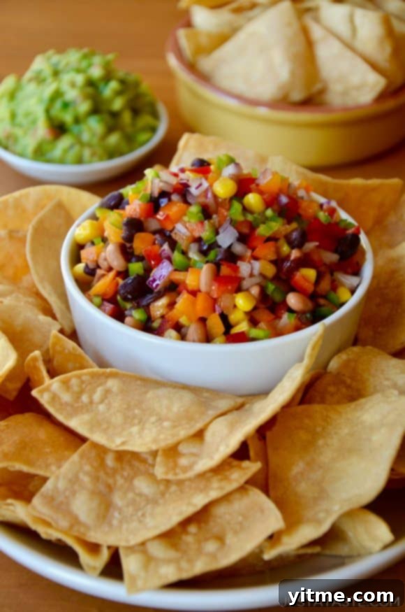 A white bowl with Texas Caviar on a plate containing tortilla chips