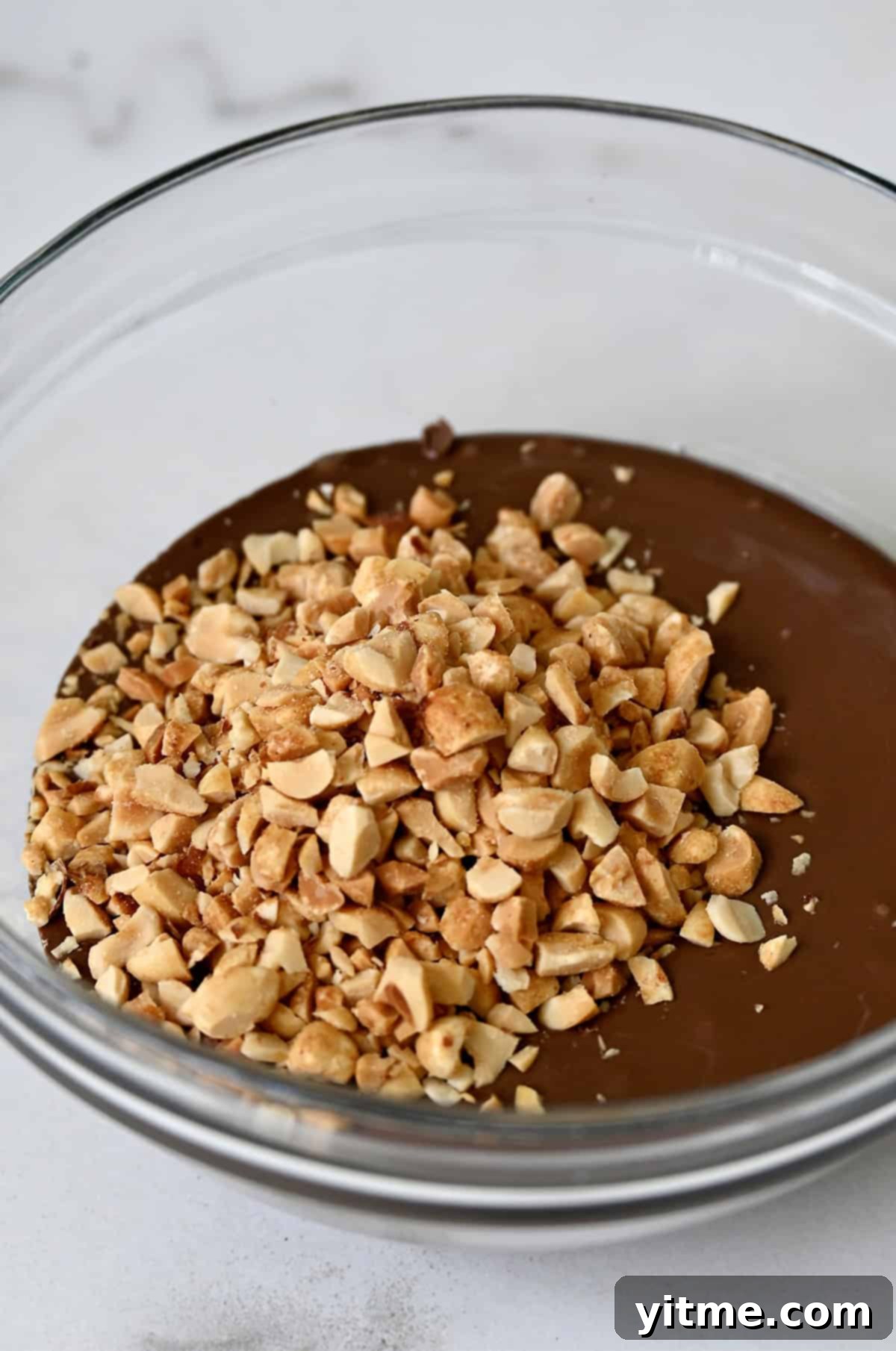 Chopped peanuts in a bowl with melted chocolate
