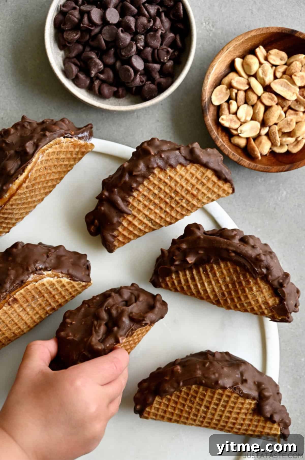 A hand reaching for a homemade choco taco on a platter
