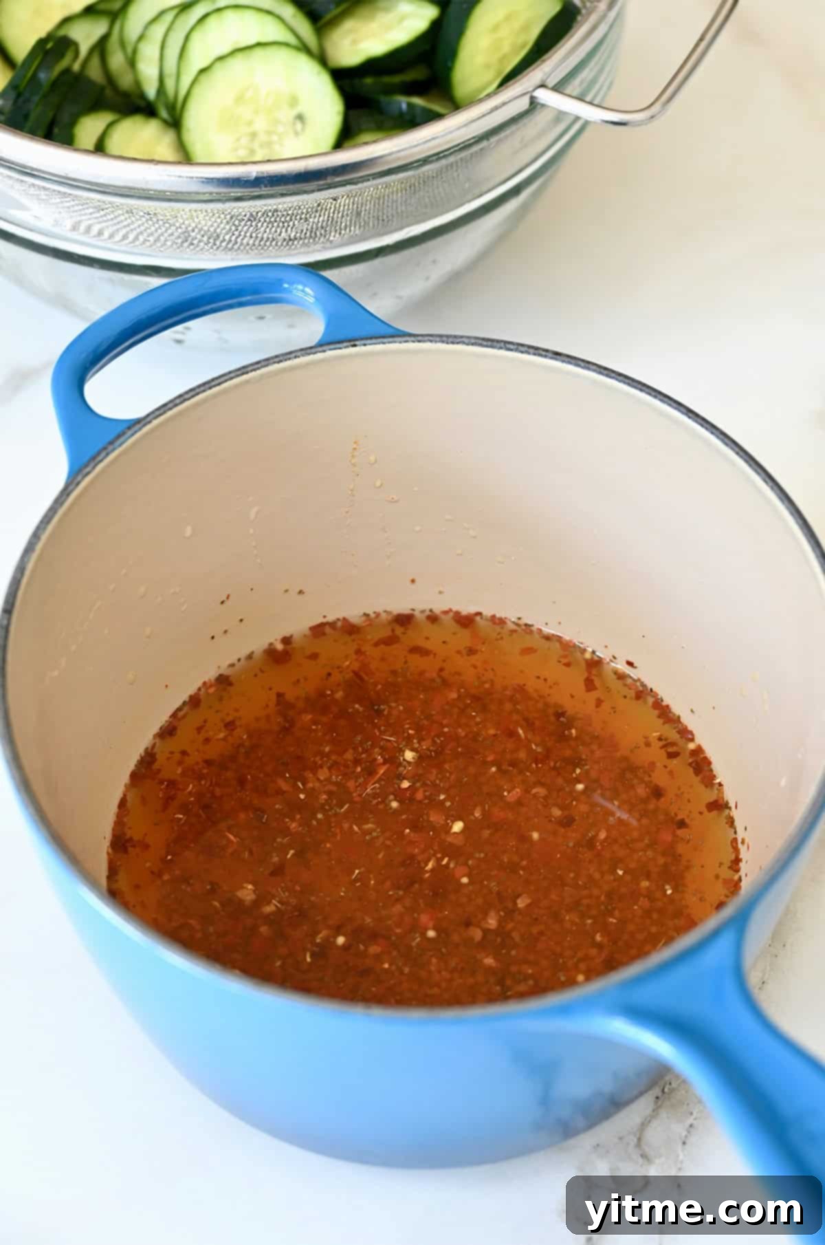 Pickling brine in a medium saucepan consisting of apple cider, sugar, water, mustard seeds, celery seeds, turmeric, bay leaf, and chili flakes.