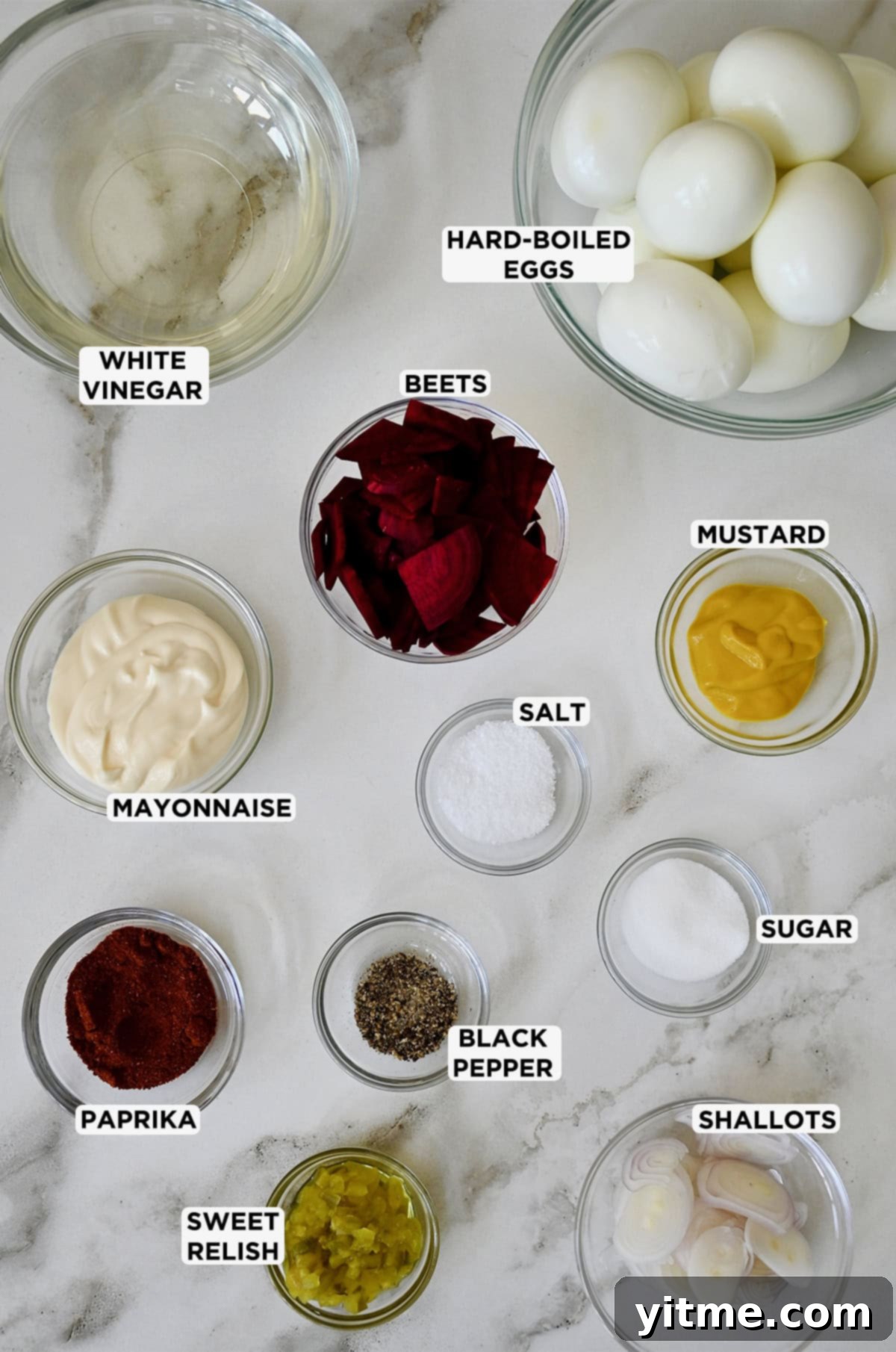 Ingredients for pickled deviled eggs: hard-boiled eggs, vinegar, beets, mayonnaise, mustard, relish, shallots, salt, sugar, pepper, and paprika.