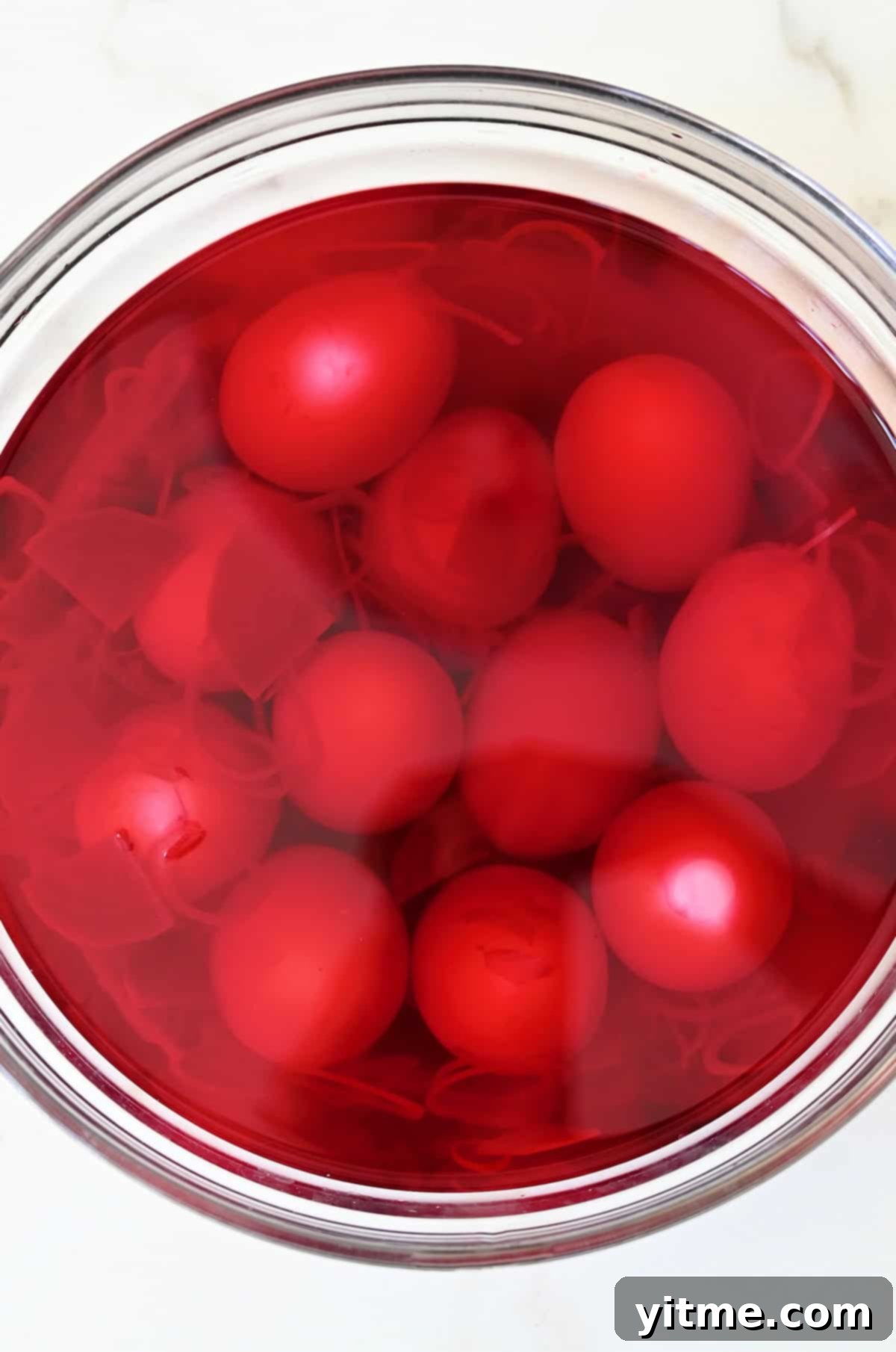 Hard-boiled eggs soaking in red pickling liquid tinted with beet juice.