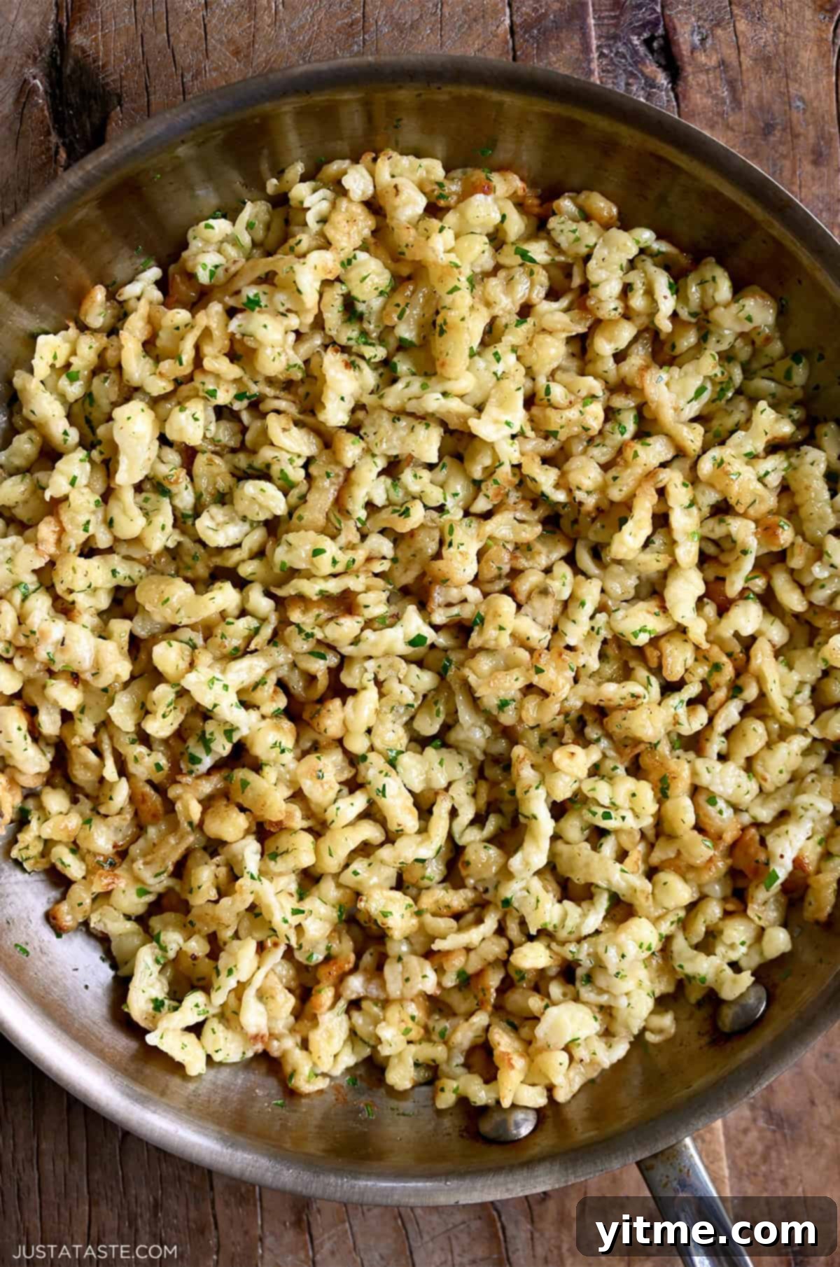 Homemade German spaetzle with melted butter and fresh parsley in a large skillet.
